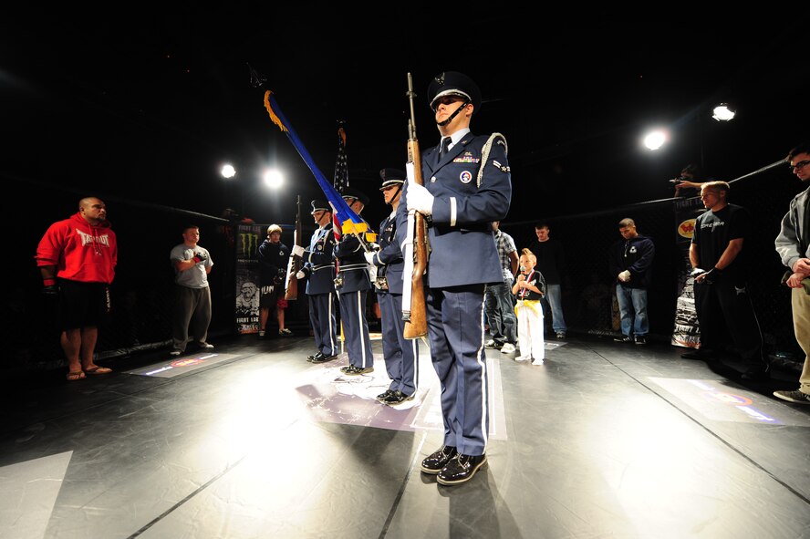 Members of the 4th Fighter Wing honor guard present the colors while a student from American Brutality Inc., sings the national anthem during the opening ceremony of a mixed martial arts event at Seymour Johnson Air Force Base, N.C., Nov. 4, 2011. Eight fights were on the card for the night, but the main event was canceled due to an opponent not showing to weigh-ins. American Brutality Inc. is a martial arts studio located in Goldsboro, N.C. (U.S. Air Force photo by Senior Airman Rae Perry)