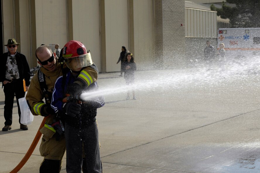 Paul Haidinger, 56ths Civil Engineer Squadron fire fighter, shows Anthony Wulfkuhle, 11, how to spray a high pressure hose to fight a fire during the Retiree Appreciation Day at Luke Air Force Base, Ariz., Nov 05, 2011. Participants were given gifts, freebees, shown displays by the U.S. Marine Corps and given flu shots. (U.S. Air Force photo by Staff Sgt. Jason Colbert)