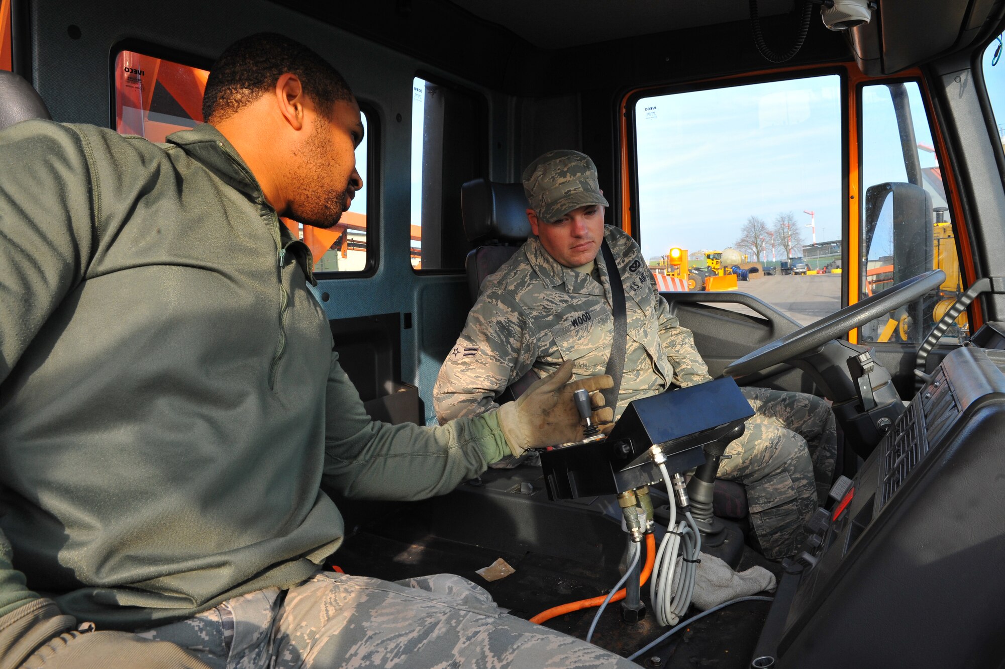 SPANGDAHLEM AIR BASE, Germany – Airman 1st Class Lorrentis Oliver, 52nd Civil Engineer Squadron heavy equipment journeyman, teaches Airman 1st Class Tyler Wood, 52nd CES heating ventilation and air conditioning apprentice, about the operation controls on a de-icing truck during annual snow control augmentee training here Nov. 8. The 52nd CES snow-control team completes annual mandatory training before they can be licensed to operate and maintain snow-removal vehicles used during winter. The team assigns 33 permanent augmentees and 10 alternate augmentees from Nov. 14 to April 15 each year for the snow season. (U.S. Air Force photo/Airman 1st Class Dillon Davis)
