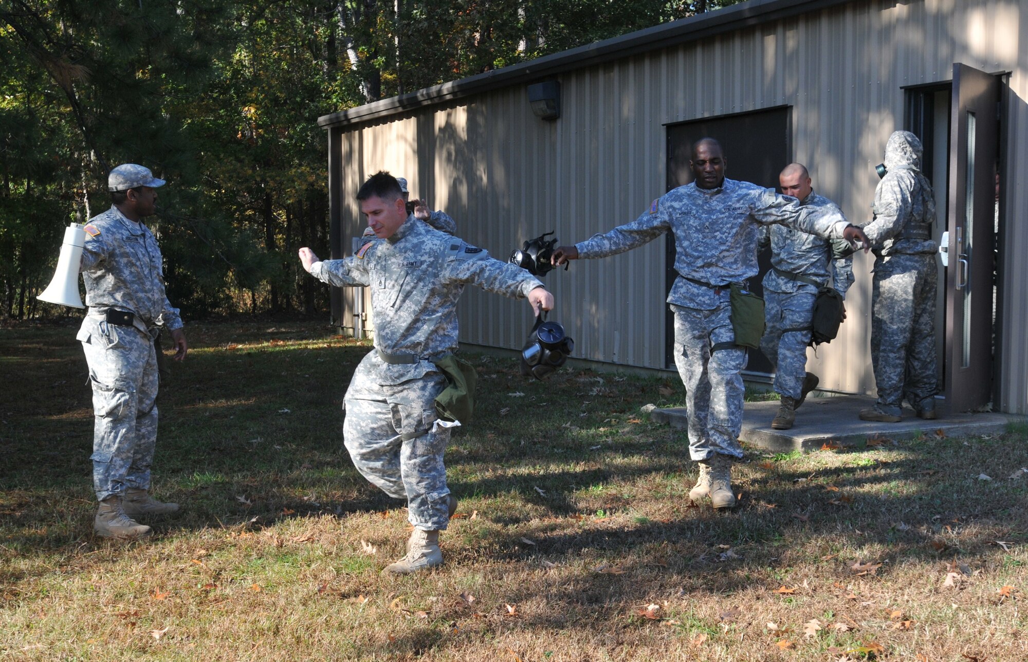 Sgt. Kyle Fergusson (far left), combat engineer, and training NCO in charge for the 331st Trans. Co., 24th Trans. Bn., 7th Sust. Bde., instructs Soldiers to keep their arms in the air and carefully walk toward the rally point upon exiting the gas chamber. (U.S. Army photo by Pfc. Alex Kilmon/RELEASED)