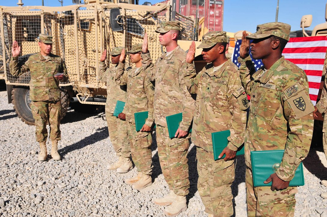 Col. Lawrence Kominiak, left, Task Force Resolute commander, issues the oath of enlistment to, from left, Spc. Ashford Turner, Sgt. Edwin Rodriguez, Sgt. Phillip Spiniao, Spc. Rashaun Moseley, and Spc. Elmore Young III, during a mass reenlistment ceremony at the Headquarters and Headquarters Company, Special Troops Battalion, TF-Resolute motorpool at Kandahar Airfield, Afghanistan, Oct. 24. (U.S. Army photo Staff Sgt. Alexander Burnett/RELEASED)