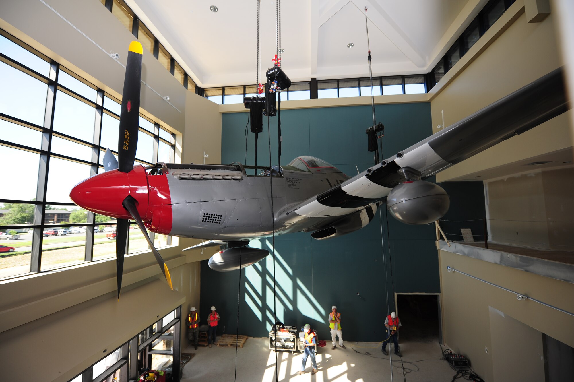 A P-51D Mustang is raised to its permanent resting spot in the newly constructed 4th Mission Support Group consolidated support center here July 15, 2011. Since the aircraft has been restored, the U.S. Air Force Museum requires it be kept inside so it is not subjected to the harsh elements found in North Carolina. (U.S. Air Force photo by Senior Airman Rae Perry)