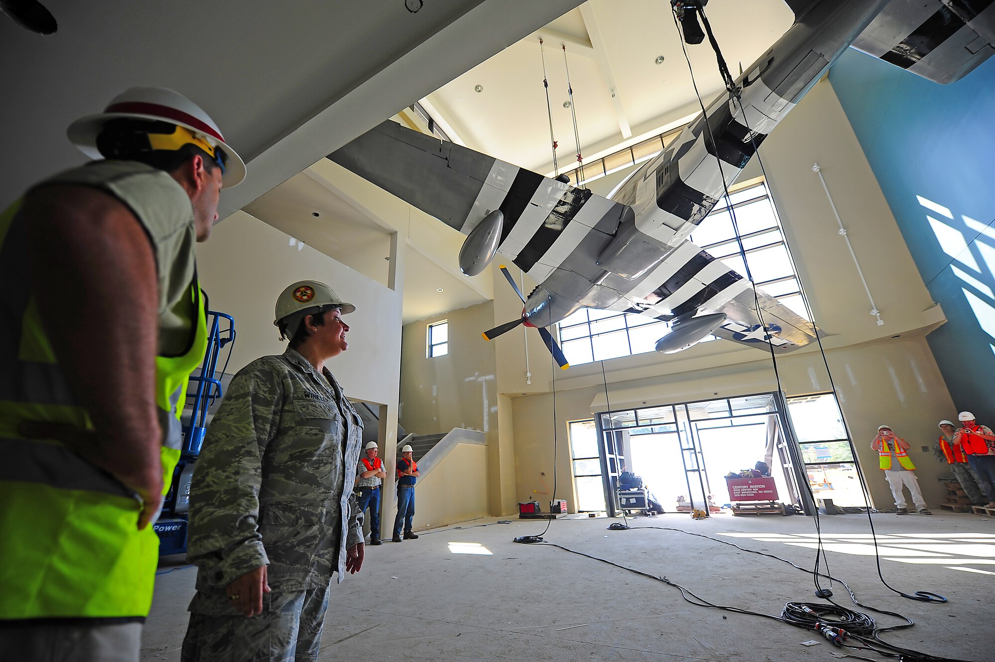 Col. Anne Winkler watches as construction crews raise a P-51D Mustang display in the under-construction 4th Mission Support Group consolidated support center here July 15, 2011. The new (CSC) will provide Airmen who are in or out processing a one stop shop to accomplish their checklist needs. Winkler, 4th MSG commander, hails from Kansas City, Mo. (U.S. Air Force photo by Senior Airman Rae Perry)