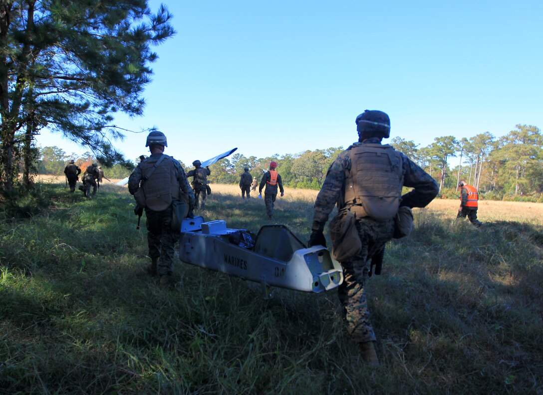 MARINE CORPS BASE CAMP LEJEUNE, N.C. – Marines and Sailors with Weapons Company, 1st Battalion, 2nd Marine Regiment, carry pieces of a crashed Unmanned Aerial Vehicle during a practice exercise for an Air Tactical Recovery of Personnel and Equipment (TRAP) course aboard Camp Lejeune, N.C. Nov. 8, 2011. The course took place Nov. 6-10 and was focused on training the Marines to conduct TRAP missions for the 24th Marine Expeditionary Unit using MV-22 Ospreys and CH-53E Super Stallions for their upcoming deployment. (Official USMC Photo by: Lance Cpl. Michael J. Petersheim/ Released)