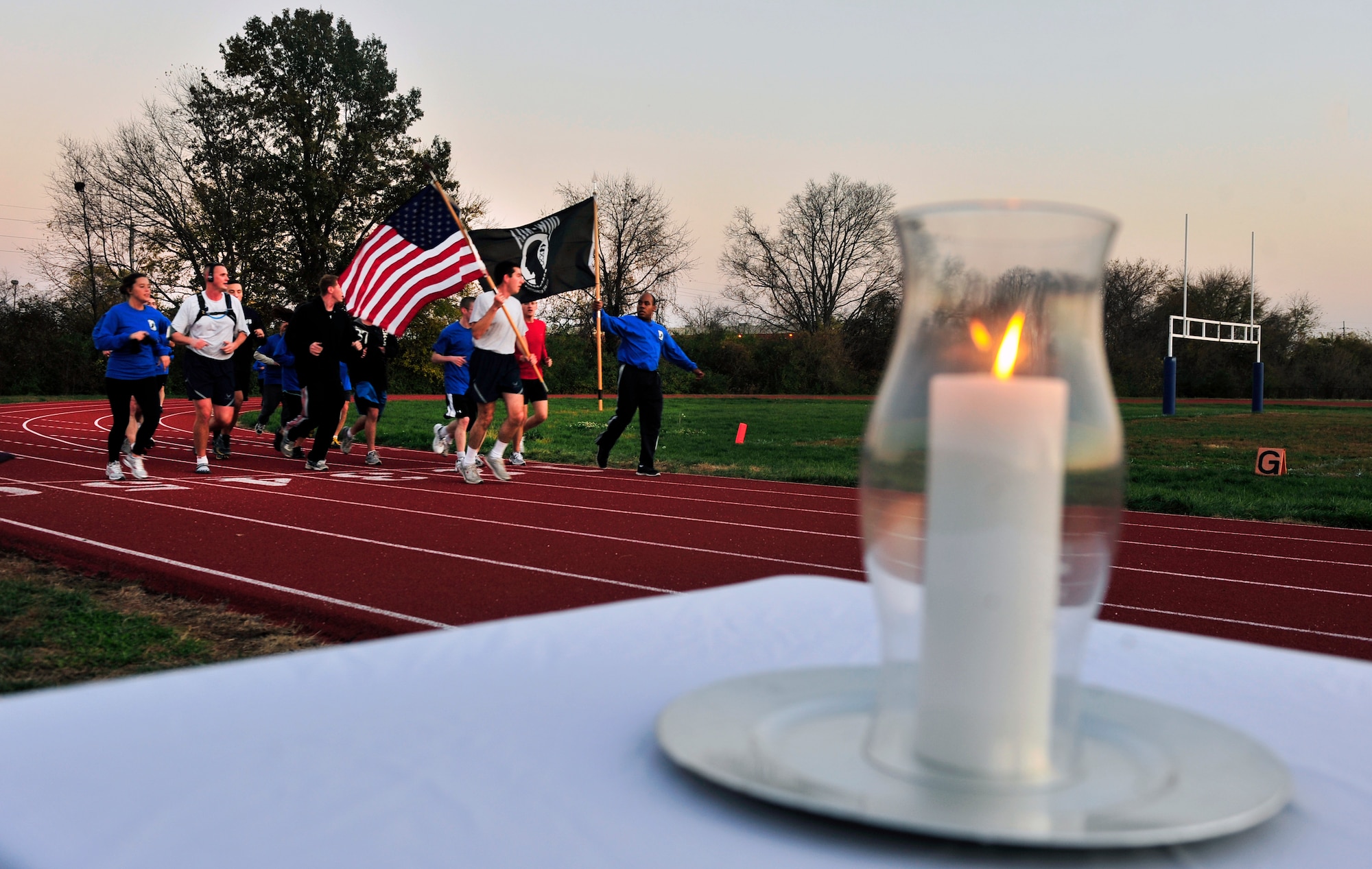 Members representing the 375th Communications Squadron run around the track on Scott AFB, Ill  Nov. 4 carrying the American flag and POW/MIA flag during  the 24-hour Air Force Sergeants Association Veterans Day Vigil relay run honoring local veteran, Senior Airman Bradley Smith from Troy, Ill. The vigil candle lit in honor of veterans past and present burned for the 24 hours relay.  (United States Air Force photo/ Staff Sgt. Stephenie Wade)