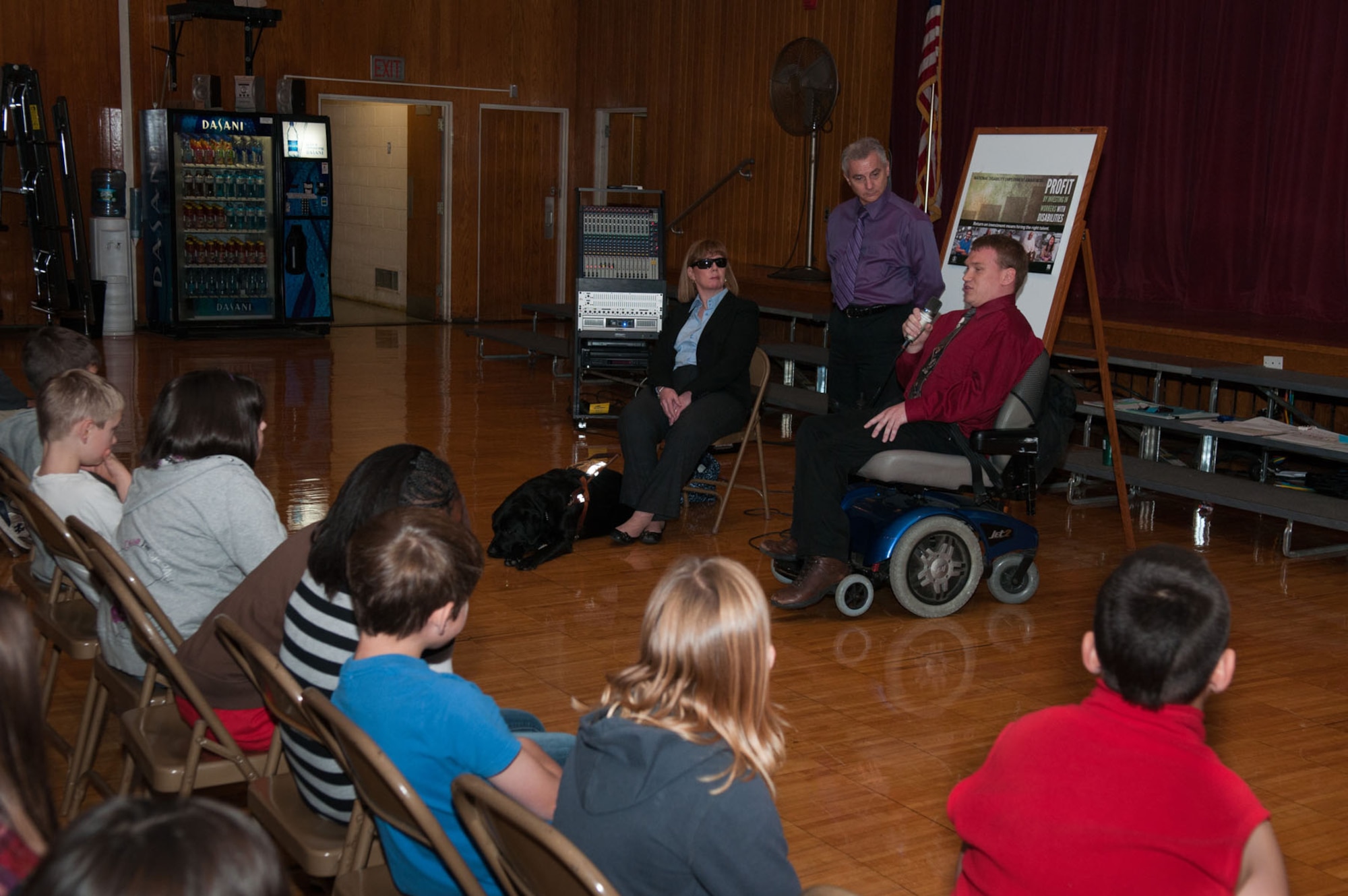 HANSCOM AIR FORCE BASE, Mass. – Members of the National Disability Employment Awareness Month committee (left to right) Maura Mazzocca with her dog, Jollie, Kim Selway and Matthew Peterson give a presentation to Hanscom Middle School fourth and fifth graders Oct. 19. The committee also recognized the National Disability Employment Awareness Month poster contest winners with certificates, ribbons and movie tickets during the presentation. (U.S. Air Force photo by Rick Berry)