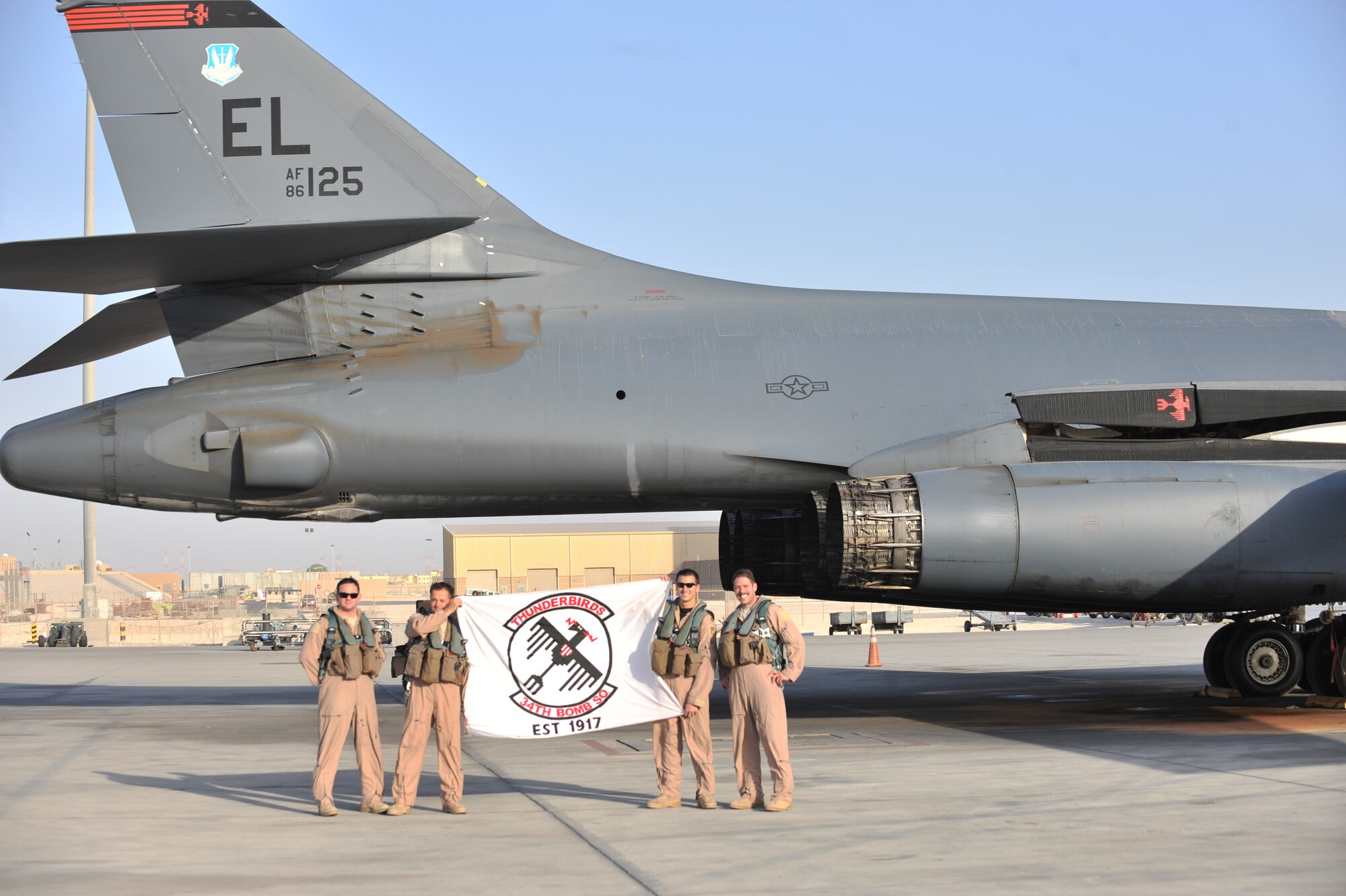 A deployed B-1B aircrew proudly displays their squadron flag following a mission in Southwest Asia Oct. 7, 2011. (U.S. Air Force photo by Senior Airman Paul Labbe/Released.)