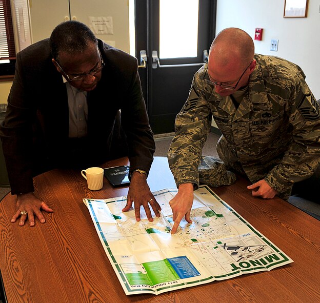 MINOT AIR FORCE BASE, N.D. -- Master Sgt. Scott Parmentier, 5th Maintenance Group product improvement manager, describes Minot’s flood damaged areas on a map to (Ret.) Lt. Gen. John D. Hopper Jr., Air Force Aid Society chief executive officer Nov. 7. Hopper visited Minot to see and hear of the recovery efforts that have taken place. As CEO, Hopper overseas The Air Force Aid Society which is a private, non-profit organization that provides emergency assistance, education grants and community support to Airmen around the world. (U.S. Air Force Photo/Airman 1st Class Desiree Esposito)

