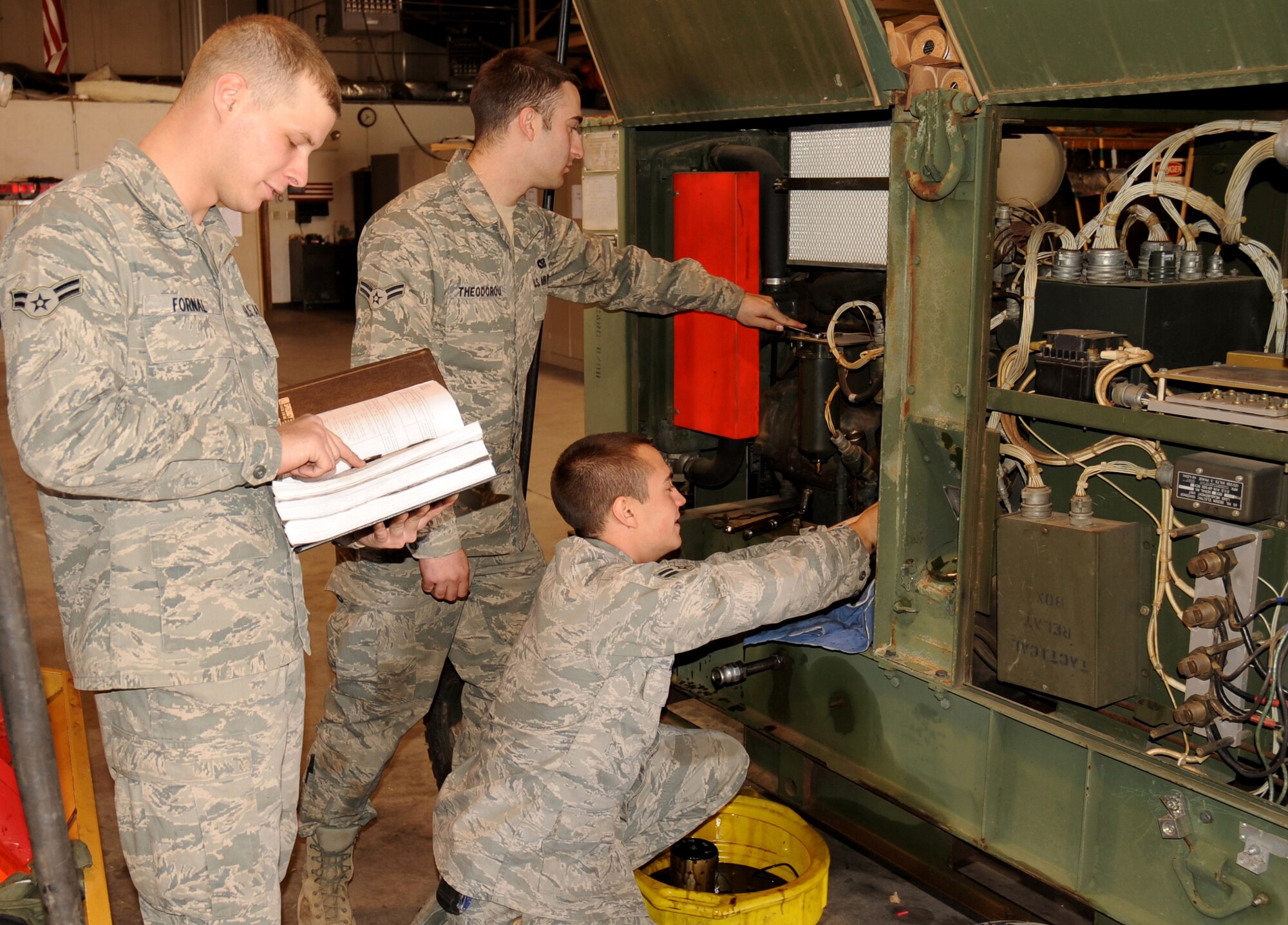 Airmen 1st Class Tyler Fornal, Steven Theodorou, and Richard Largey siphon out oil from one of their generators and check key components while performing routine maintenance at Cannon Air Force Base, N.M., Nov. 8, 2011. All three Airmen are technicians in the 27th Special Operations Civil Engineer Squadron power production shop, and are responsible for providing power to essential components on base. (U.S. Air Force photo by Airman 1st Class Alexxis Pons Abascal)        