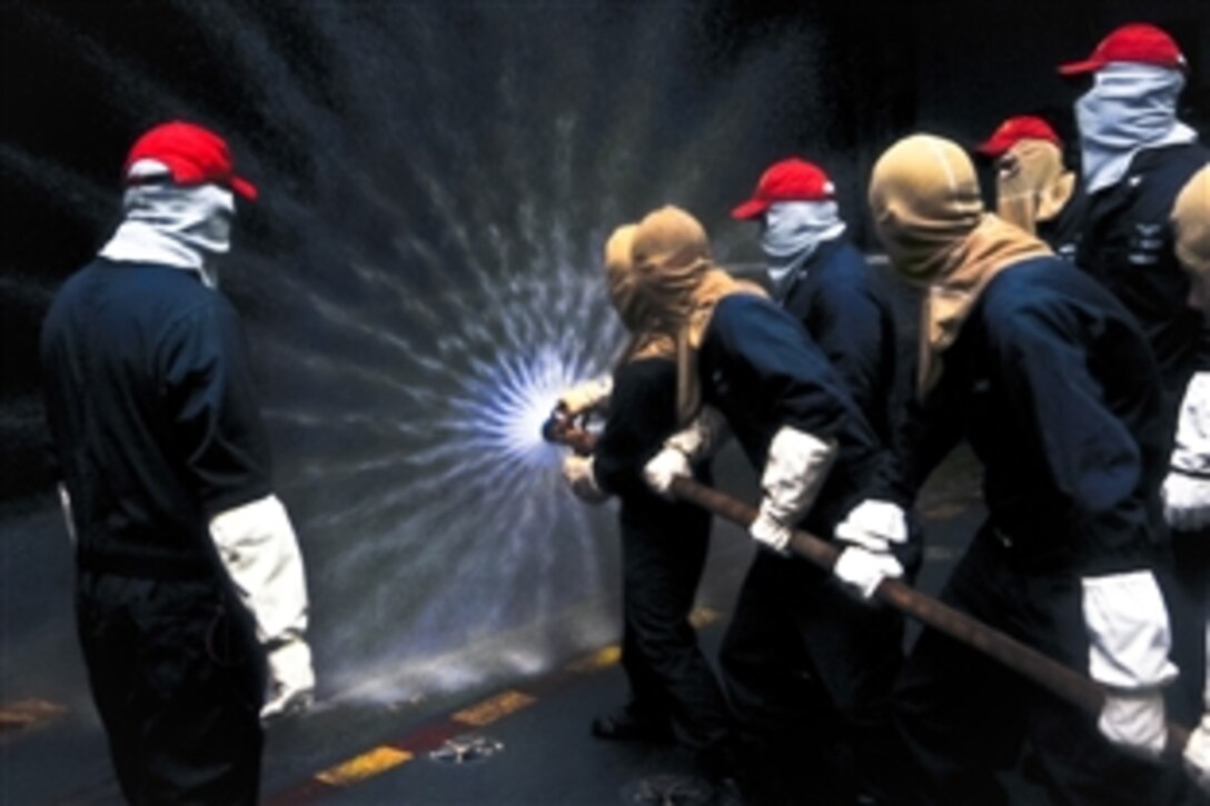 U.S. Navy sailors aboard the aircraft carrier USS George Washington practice fire hose handling techniques during a general quarters drill while under way in the South China Sea, Nov 7, 2011. 