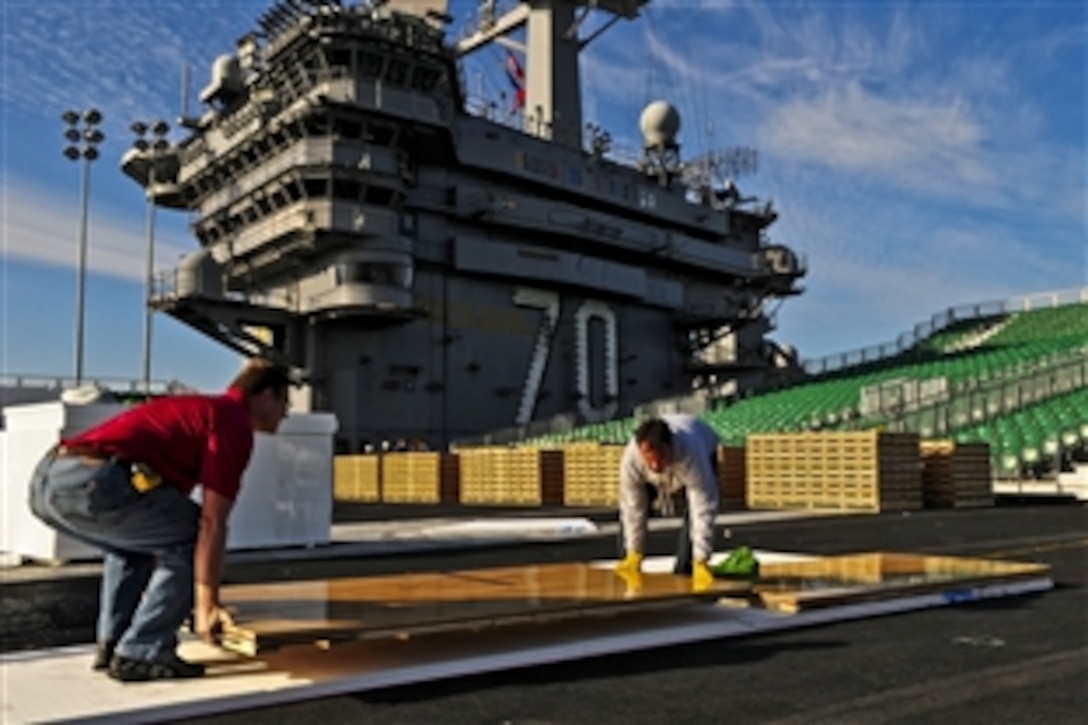 McWil Sport Surfaces employees begin laying the hardwood floor for a basketball court aboard the aircraft carrier USS Carl Vinson in San Diego, Nov. 8, 2011. The Carl Vinson is preparing to host the Michigan State University Spartans and the University of North Carolina Tar Heels for the inaugural Quicken Loans Carrier Classic basketball game on Veterans Day, Nov. 11, 2011. 
