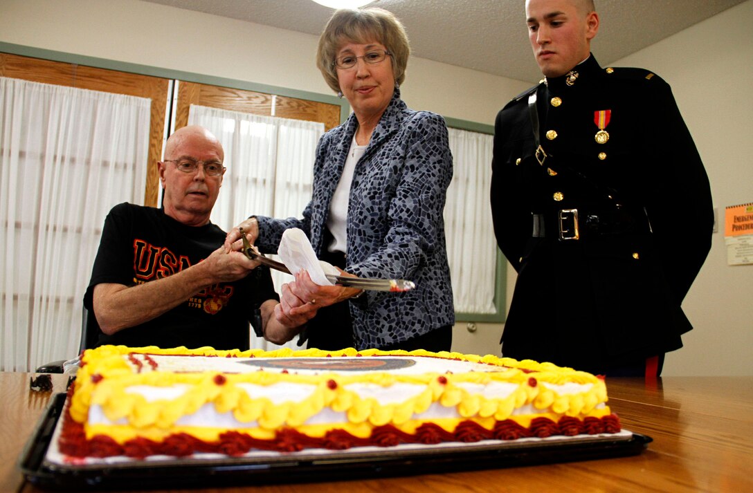 Retired Maj. John McGee(left) cuts a Marine Corps Birthday cake with the assistance of his wife Beverly(middle) during the commissioning of their son 2nd Lt. Mark McGee(Right) and Marine Corps Birthday cake cutting ceremony, Nov. 10.