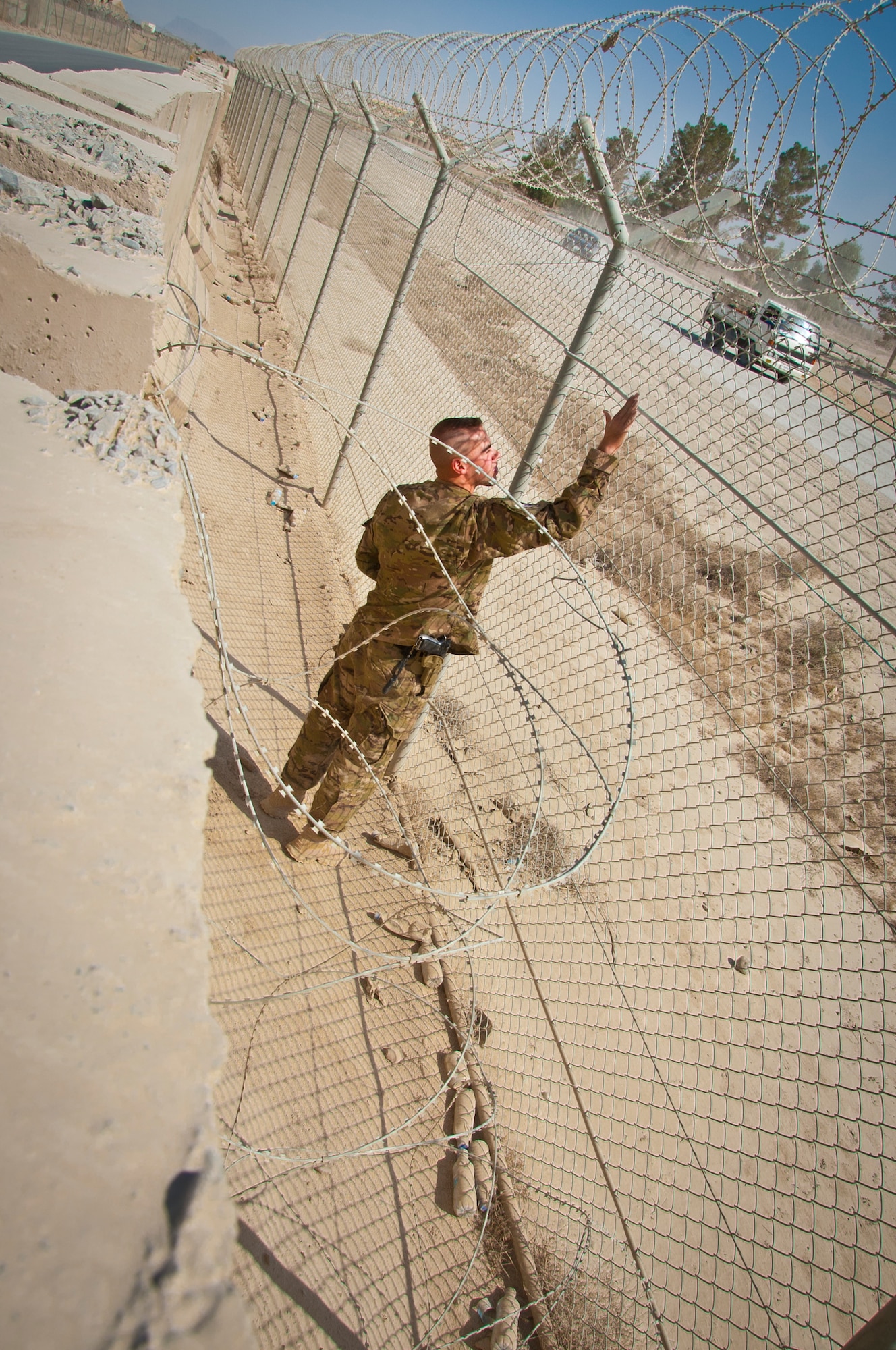 KANDAHAR AIRFIELD, Afghanistan -- Staff Sgt. Alan Dickinson, 451st Air Expeditionary Wing Tactical Automated Security System NCO in charge, checks the integrity of the perimeter fence during a routine inspection Oct. 28. Approximately 11 miles of perimeter fence is in place separating the base from the local Afghanistan community. (U.S. Air Force photo by Senior Airman David Carbajal)