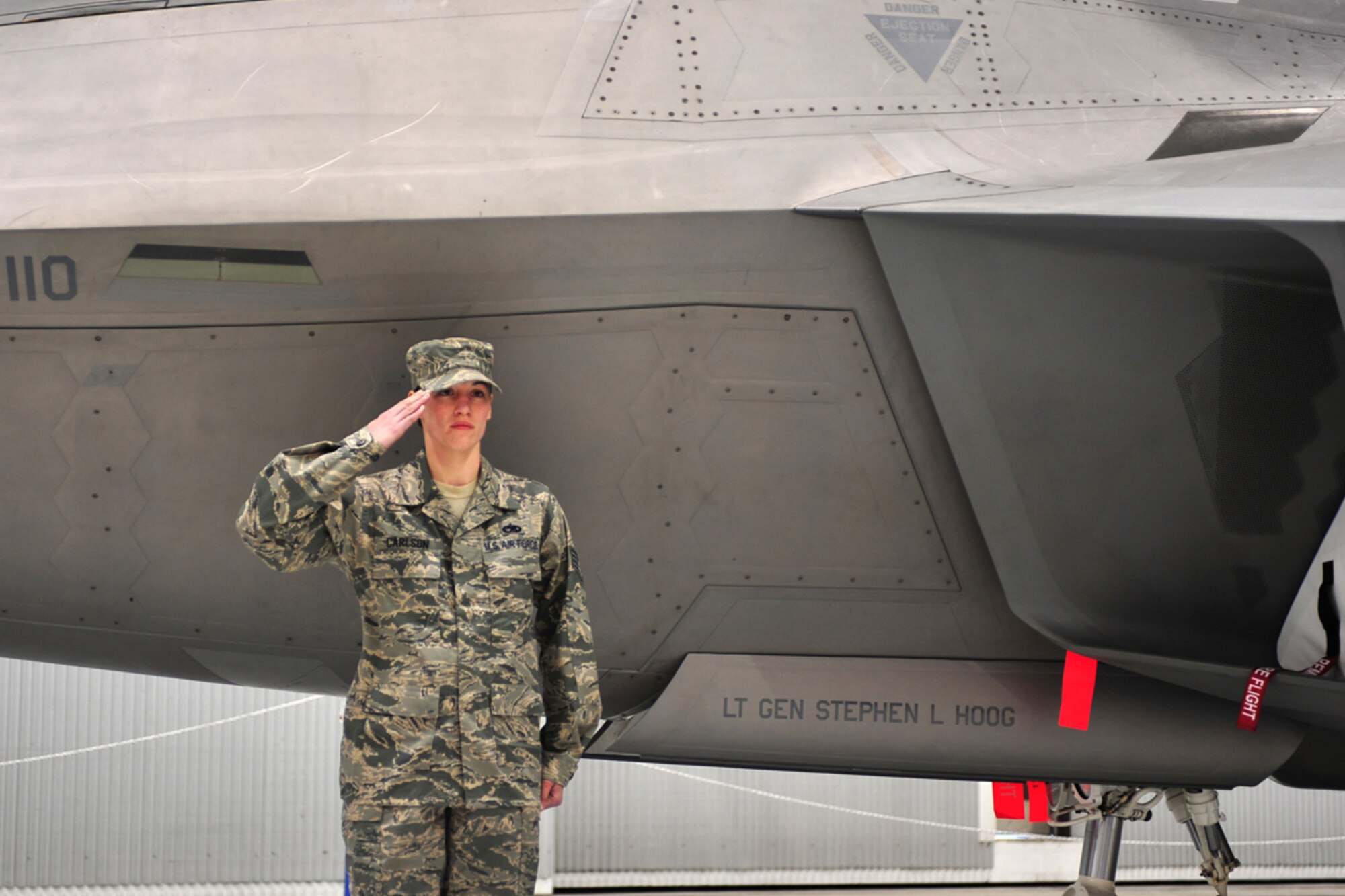 Staff Sgt. Maria Carlson, 525th Aircraft Maintenance Unit, salutes Lt. Gen. Stephen Hoog after unveiling his name on an F-22 Raptor during the Alaskan Command, Eleventh Air Force, Alaskan North American Aerospace Defense Command Region and Joint Task Force Alaska change of command ceremony at Joint Base Elmendorf-Richardson, Nov. 7. Hoog assumed command from Lt. Gen. Dana Atkins, who is retiring from the Air Force after 36 years of service.  (U.S. Air Force photo/Staff Sgt. Sheila deVera)
