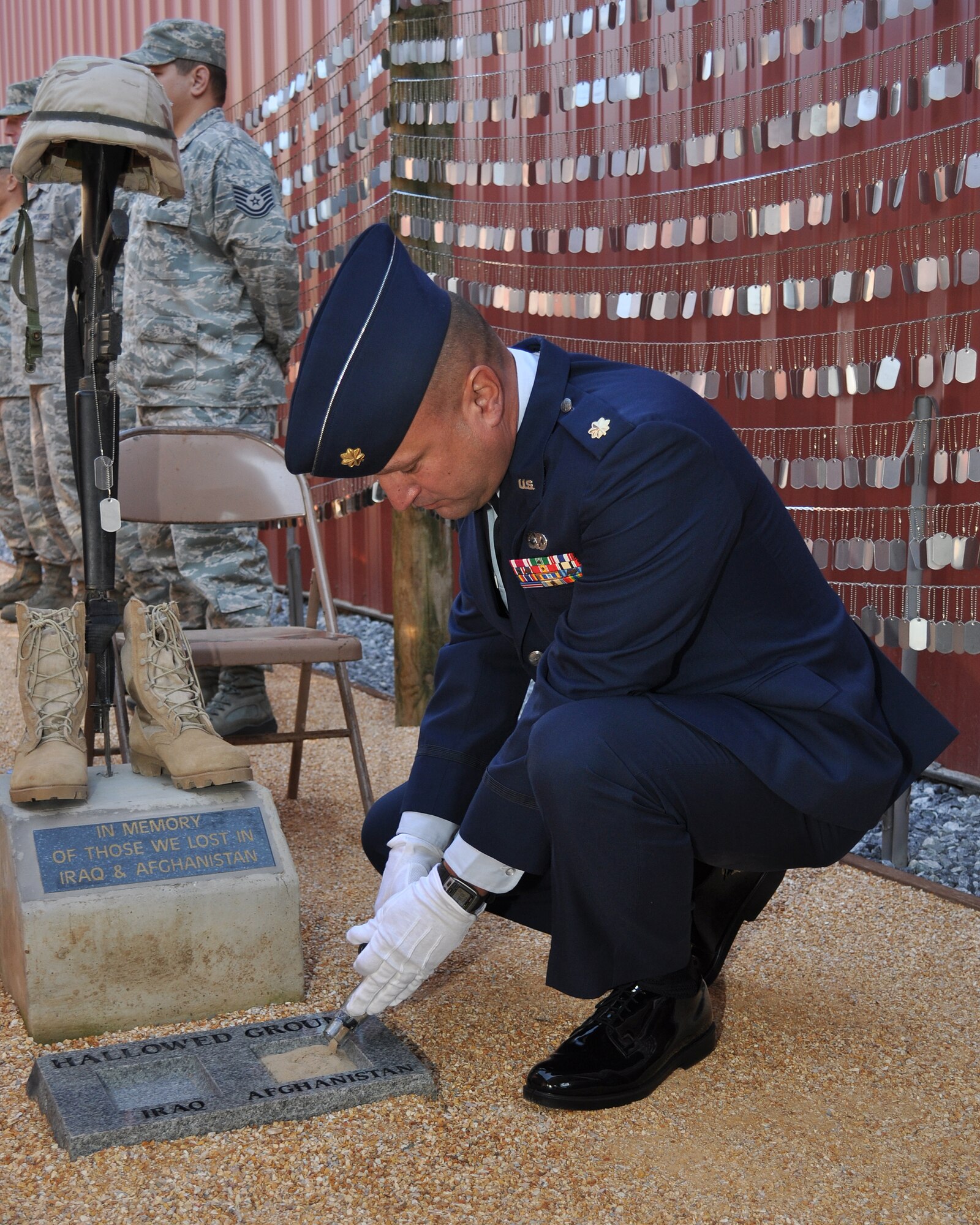 U.S. Air Force Maj. Cary Simpson, 349th Logistics Readiness Squadron plans officer, pours sand from Afghanistan onto a memorial during a ceremony at the Museum of the Forgotten Warrior outside of Beale Air Force Base, Calif., Nov. 10, 2011. The memorial was built to honor all of the servicemembers who have been killed during the Iraq and Afghanistan Wars as of October 30, 2011, containing over 6296 individual dog tags.  (U.S. Air Force photo by Staff Sgt. Jonathan Fowler/Released)