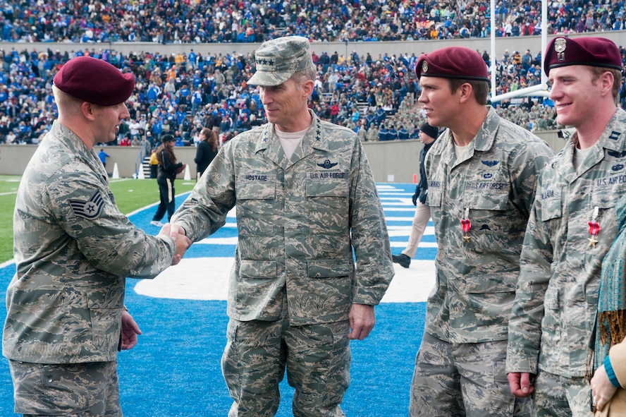 U.S. Air Force Staff Sgt. Lucas Ferrari, 48th Rescue Squadron, Davis-Monthan Air Force Base, Ariz., which is a geographically separated unit to the 23rd Wing, Moody Air Force Base, Ga., shakes hands with U.S. Air Force Gen. Mike Hostage, commander Air Combat Command, during half-time of the Army vs. Air Force football game at the U.S. Air Force Academy, Colorado Springs, Colo., on Nov. 5, 2011. Hostage presented Ferrari with the Distinguished Flying Cross during  half-time, as well as Bronze Stars to  U.S. Air Force Staff Sgt. Mark Lillmars, middle right, also with the 48th RQS, and U.S. Air Force Captain Francis Hallada, far right, 58th Rescue Squadron from Nellis Air Force Base, Nev., which is also  a GSU of the 23rd Wing.
