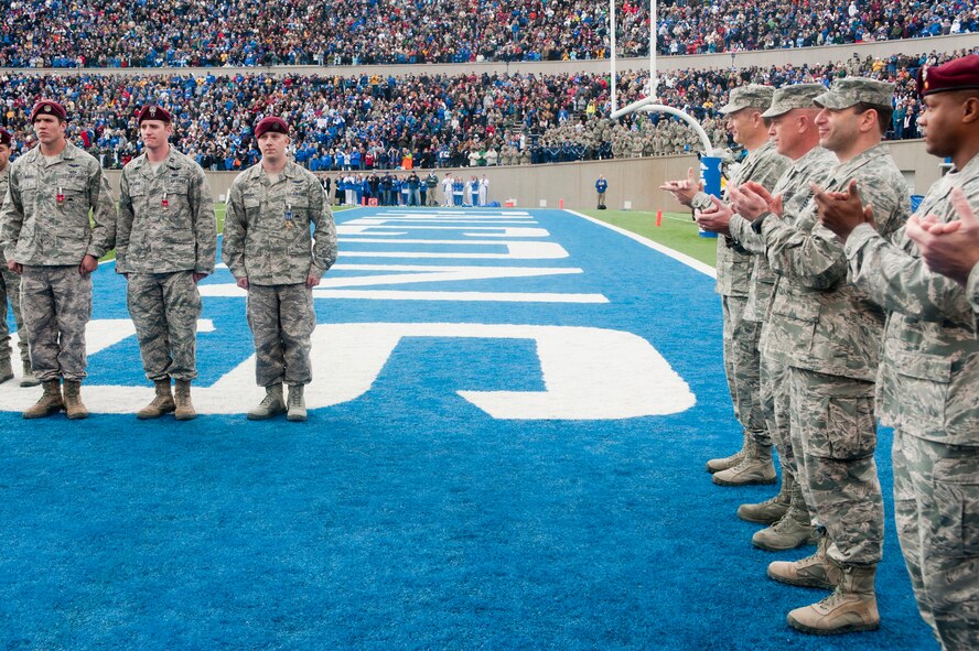 U.S. Air Force Staff Sgt. Mark Lillmars, 48th Rescue Squadron, Davis-Monthan Air Force Base, Ariz., a geographical separated unit  of the 23rd Wing, Moody Air Force Base, Ga., U.S. Air Force Captain Francis Hallada, 58th Rescue Squadron from Nellis Air Force  Base, Nev., also a GSU of the 23rd Wing, and U.S. Air Force Staff Sgt. Lucas Ferrari, also with the 48th RQS, are applauded by 23rd Wing leadership and the audience of the Army vs. Air Force football game at the U.S. Air Force Academy, Colorado Springs, Colo. Nov. 5, 2011. Lillmars and Hallada received Bronze Stars for their service while deployed to Afghanistan, where their actions directly contributed to the safety of injured personnel. Ferrari received the Distinguished Flying Cross for his actions while also deployed to Afghanistan, where he performed cricothyrotomy surgery on an injured service member en-route to the hospital on a HH-60 Pave Hawk. (U.S. Air Force Photo by Staff Sgt. Joshua J. Garcia/ Released)