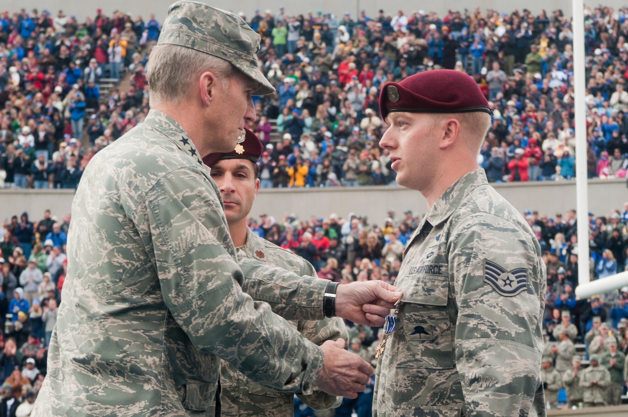 U.S. Air Force Gen. Mike Hostage, commander of Air Combat Command, presents the Distinguished Flying Cross to U.S. Air Force Staff Sgt. Lucas Ferrari, 48th Rescue Squadron, Davis-Monthan Air Force Base, Ariz., a geographically separated unit of the 23rd Wing, Moody Air Force Base, Ga., during half-time of the Army vs. Air Force football game at the U.S. Air Force Academy, Colorado Springs, Colo., on Nov. 5, 2011.  Ferrari received the medal for his actions while deployed to Afghanistan, where his medical expertise ensured the survival of critically injured personnel during an urgent casualty evacuation mission. (U.S. Air Force photo by Staff Sgt. Joshua J. Garcia/Released)