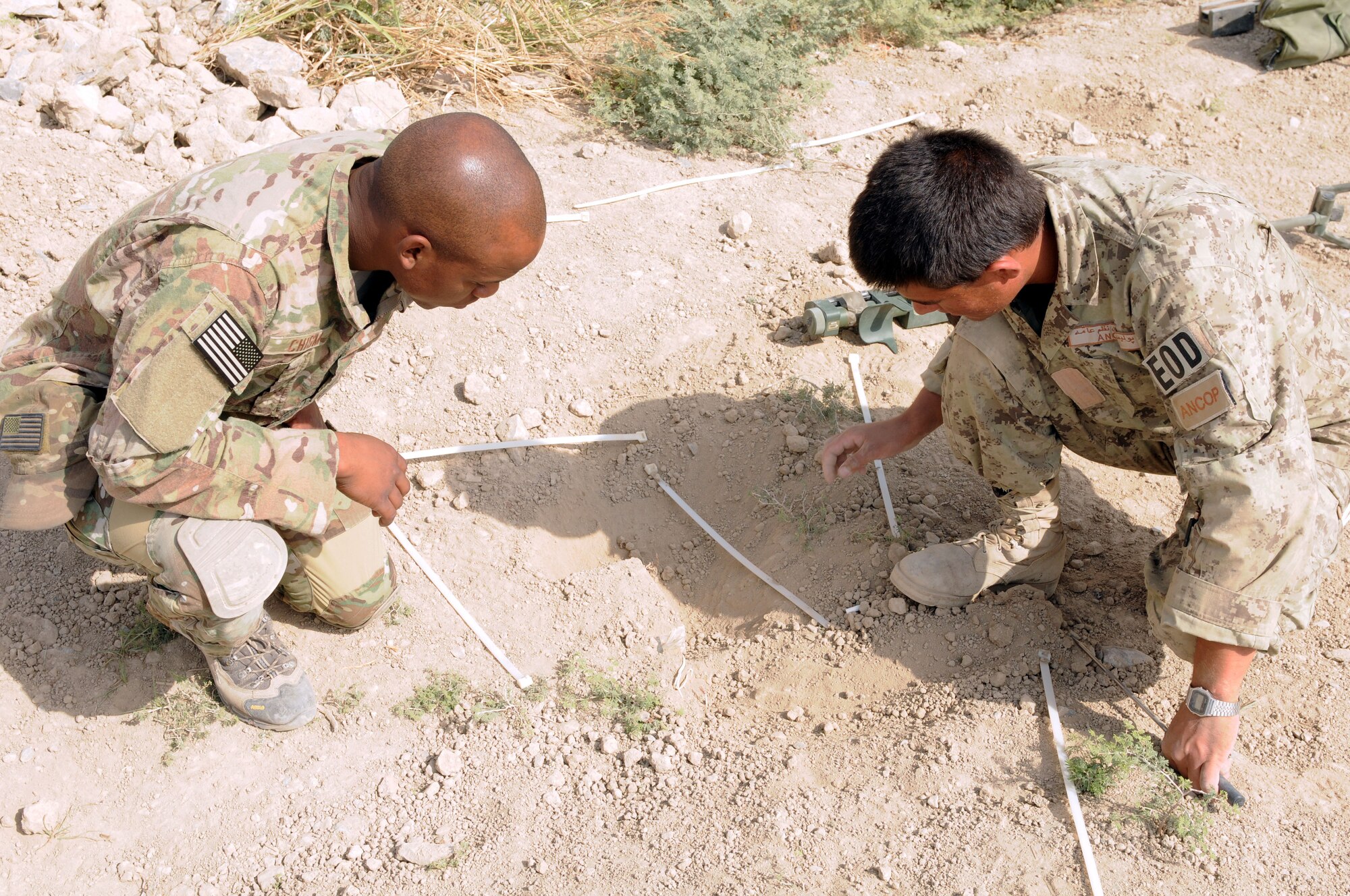 Air Force Staff Sgt. Brandon Chism, explosive ordnance disposal technician with the 466th Air Expeditionary Squadron, talks with and mentors Afghan National Civil Order Police Sgt. Nasrullah Mohammad Sharif, also an EOD technician, Oct. 23. Chism, and his teammates, set up weekly training sessions with the ANCOP, in order to validate their technical skills in detecting, extracting and safely clearing IEDs. (U.S. Army photo by Staff Sgt. Lindsey Kibler)