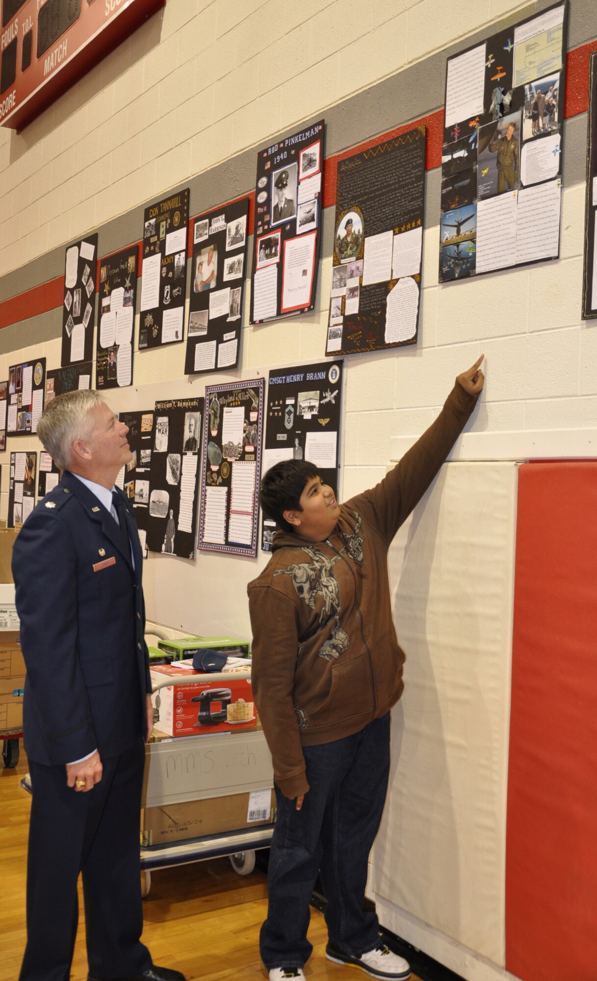 Meet Kapadia,12, a student at Maize Middle School shows Lt. Col. Barry Jones, Commander, 931st Operations Support Squadron his Veterans Day project following a Veterans Day program at the school. The photo essay details Jones' duties at the 931st Air Refueling Group. Administrators, teachers and students from Maize Middle School invited veterans to attend a ceremony at their school, Nov. 11. (Air Force photo by Brannen Parrish).