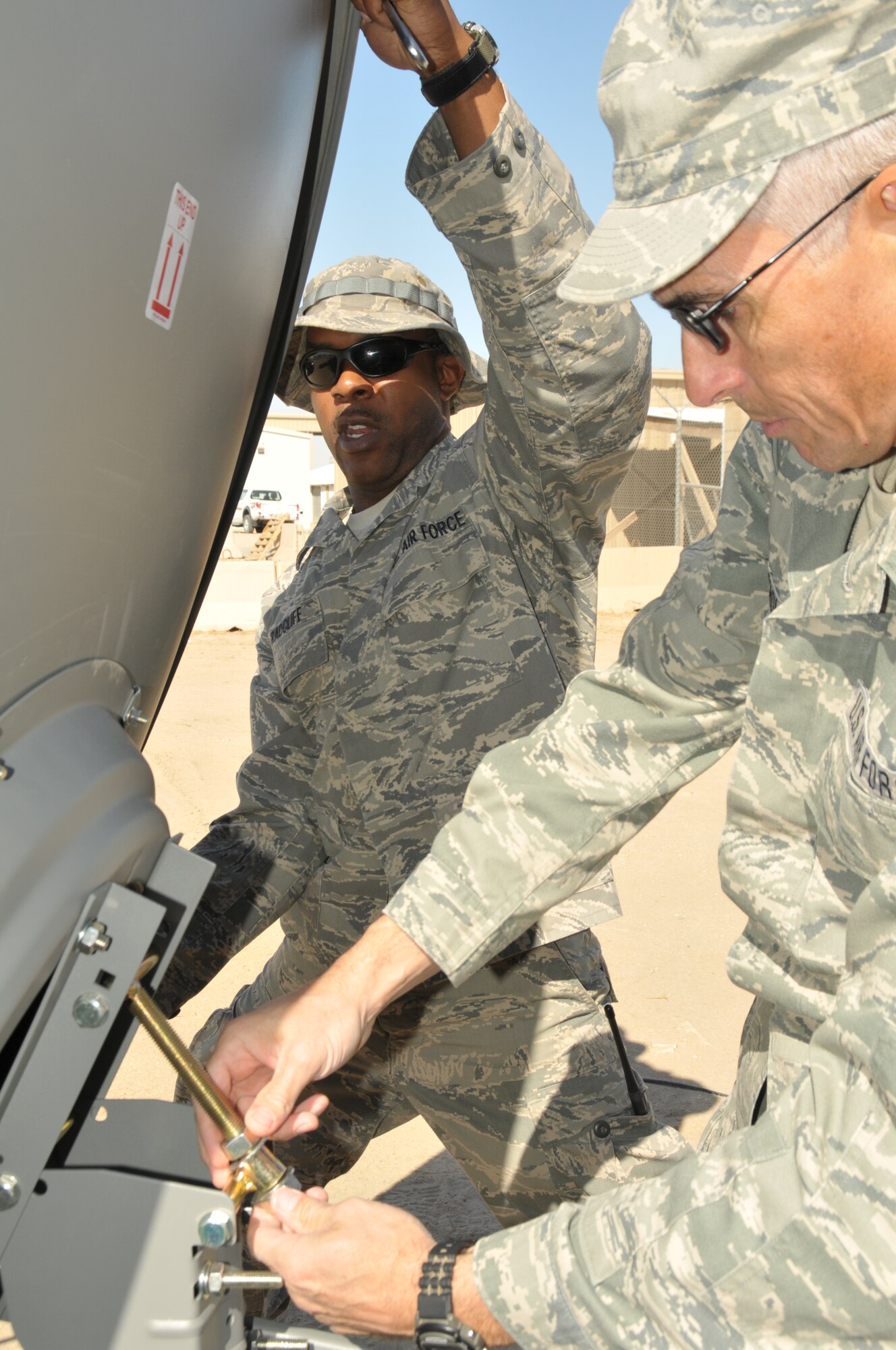Staff Sgt. Arel Radcliff and Senior Airman Robert Nicholson, both 332nd Expeditionary Communications Squadron radio frequency transmission technicians, adjust the angle of a new American Forces Network satellite dish at an undisclosed location in Southwest Asia Nov. 10, 2011. Both Airmen, who are deployed from the 263rd Combat Communications Squadron, North Carolina Air National Guard, installed the AFN dish to provide 332nd AEW members access to the network's programs. Radcliff is a native of Salisbury, N.C., and Nicholson calls Wilmington, N.C., home. (U.S. Air Force photo by Master Sgt. Paul Mann)
