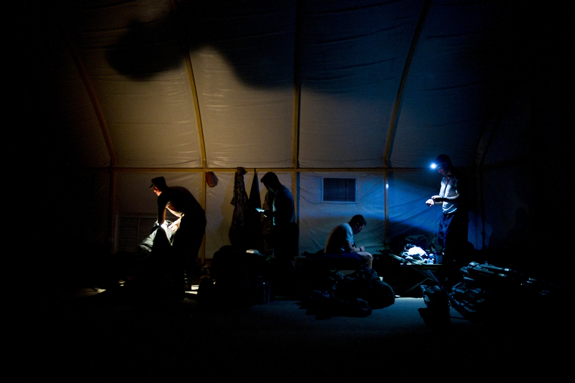 Members of the 70th medium truck detachment use flashlights to see while they pack their bags as they begin the second day of their seven day convoy through Iraq on Oct. 24, 2011. Several different convoys stop at the same location and share limited tent space between legs of their trips. (U.S. Air Force Photo/Master Sgt. Jeffrey Allen)