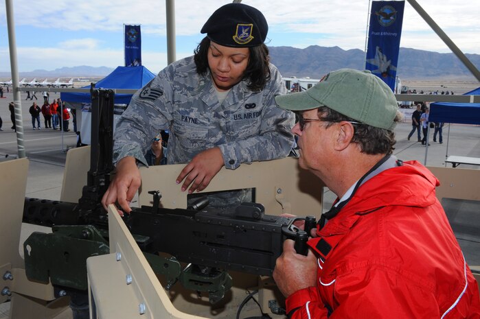 U.S. Air Force Staff Sgt. Alverdite Payne, 99th Security Forces Squadron, demonstrates how to use the 50. caliber machine gun mounted on a humvee to Rick Fey during the 2011 Aviation Nation Open House Nov. 12, at Nellis Air Force Base, Nev.  Aviation Nation celebrates 70 years of airpower in Las Vegas and the Air Force's accomplishments in air, space and cyberspace.  (U.S. Air Force photo by Staff Sgt. William P.Coleman/Released)  