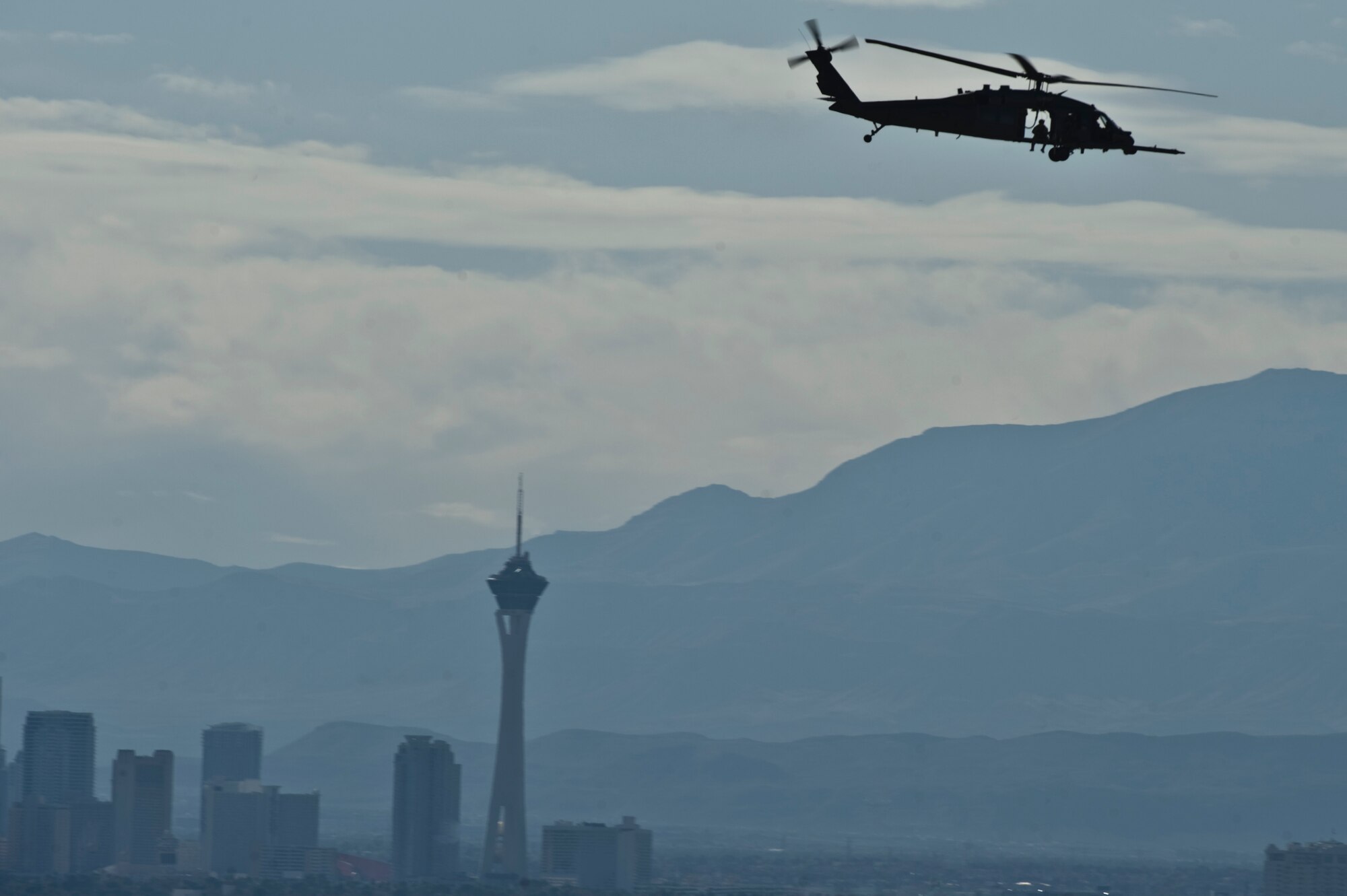 A U.S. Air Force pararescueman sits in an HH-60 Pavehawk as it flies over the flightline as part of a Present Day Air-to- Ground Mission Demonstration during the 2011 Aviation Nation Open House Nov. 12, at Nellis Air Force Base, Nev. Aviation Nation celebrates 70 years of airpower in Las Vegas and the Air Force's accomplishments in air, space and cyberspace. (U.S. Air Force photo by Airman 1st Class Daniel Hughes/Released)

