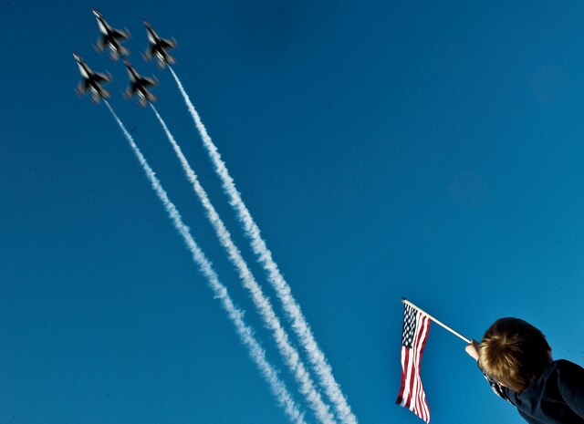 A boy holds up an American Flag as the United States Air Force Air Demonstration Squadron Thunderbirds, fly overhead during the 2011 Aviation Nation Open House Nov. 12, at Nellis Air Force Base, Nev. Aviation Nation celebrates 70 years of airpower in Las Vegas and the Air Force's accomplishments in air, space and cyberspace. (U.S. Air Force photo by Staff Sgt. Christopher Hubenthal/Released)