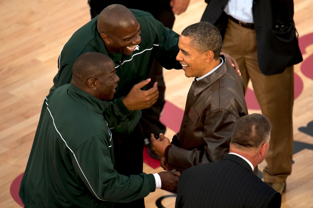 NBA Hall of Fame basketball player Earvin "Magic" Johnson, center, and Michigan State University assistant coach Mike Garland greet President Barack Obama on the court at the Quicken Loans Carrier Classic aboard the USS Carl Vinson in San Siego, Nov. 11, 2011. Carl Vinson hosted Michigan State University and the University of North Carolina for an NCAA basketball game.