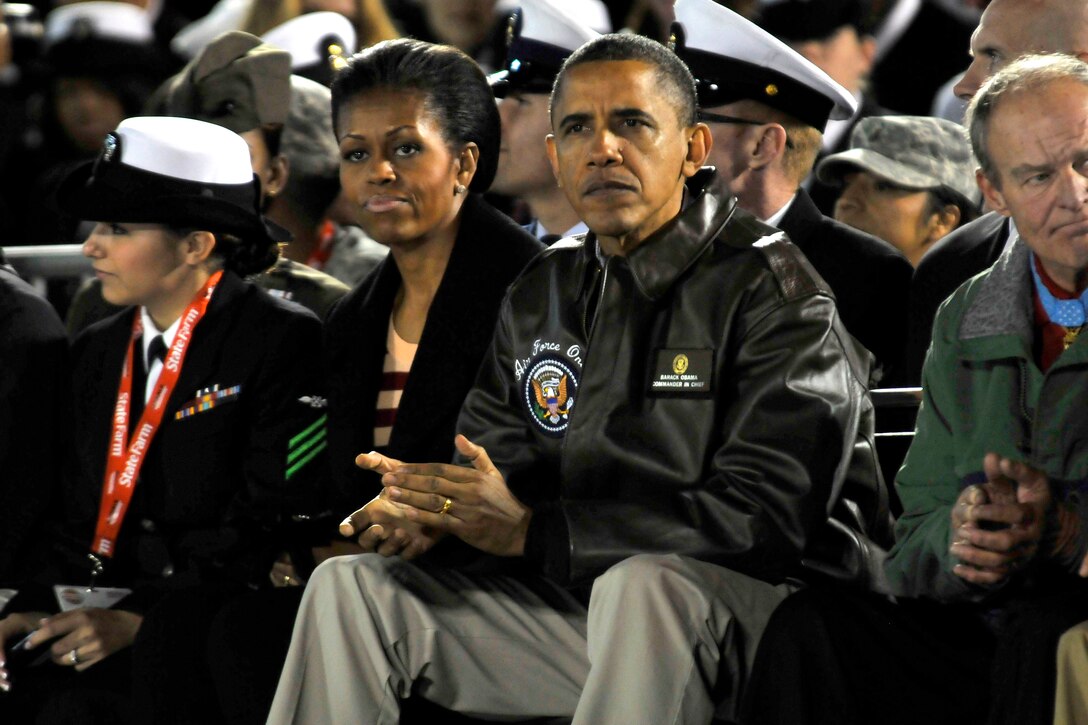President Barack Obama and First Lady Michelle Obama sit amognst service members and watch the Quicken Loans Carrier Classic aboard the USS Carl Vinson in San Diego, Nov. 11, 2011. 