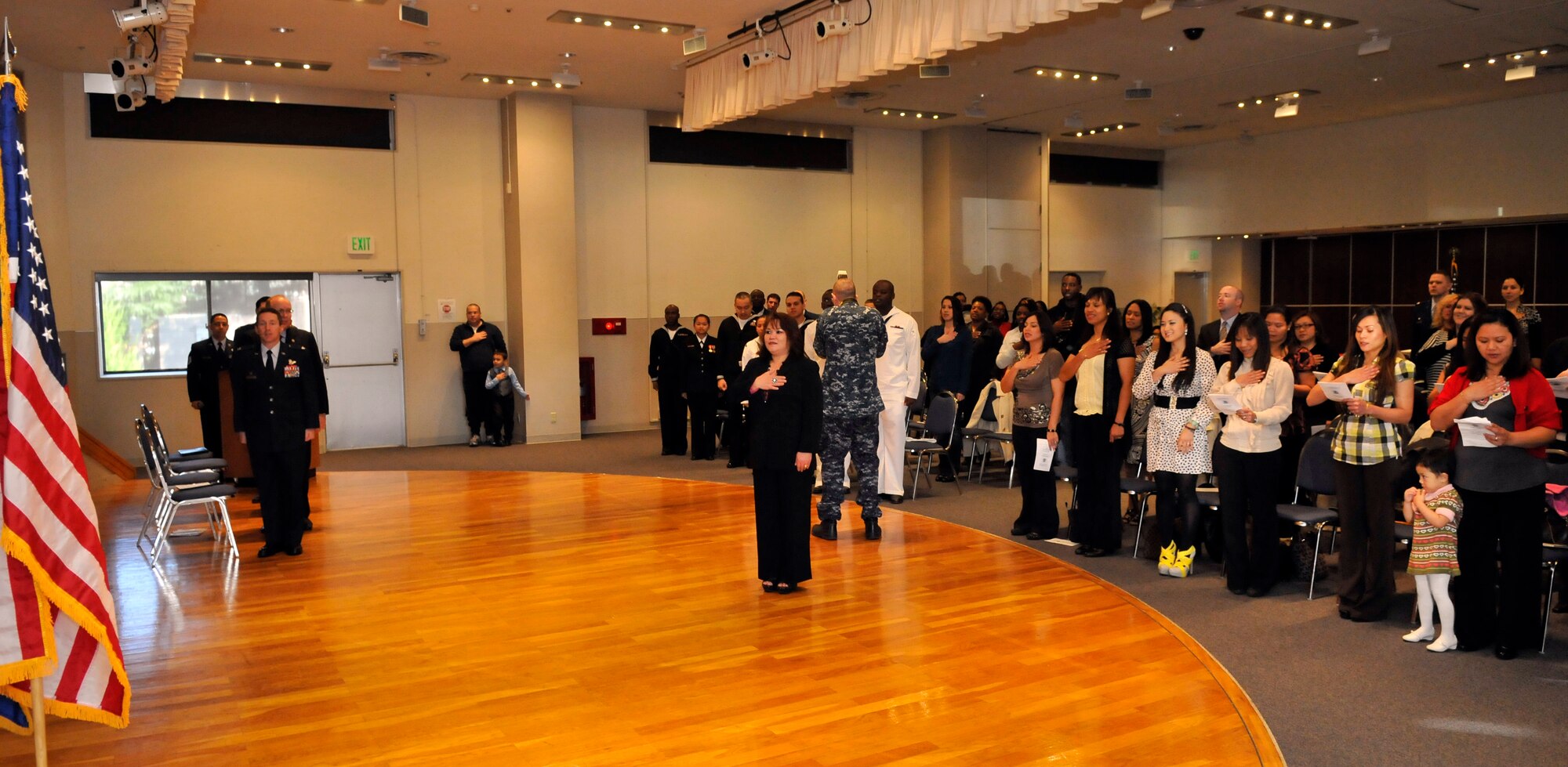 MISAWA AIR BASE, Japan – Jenny Gammage, wife of Chief Master Sergeant John Gammage, 35th Security Force Squadron chief enlisted advisor, leads the auditorium in the pledge of allegiance here Nov.11. Only 21 of the original 26 prospective American citizens were allowed to attend the oath of allegiance ceremony.  For the first time, USCIS agents have come to Misawa to test prospective American citizens and administer the oath of allegiance. (U.S. Air Force photo by Tech. Sgt. Phillip Butterfield)