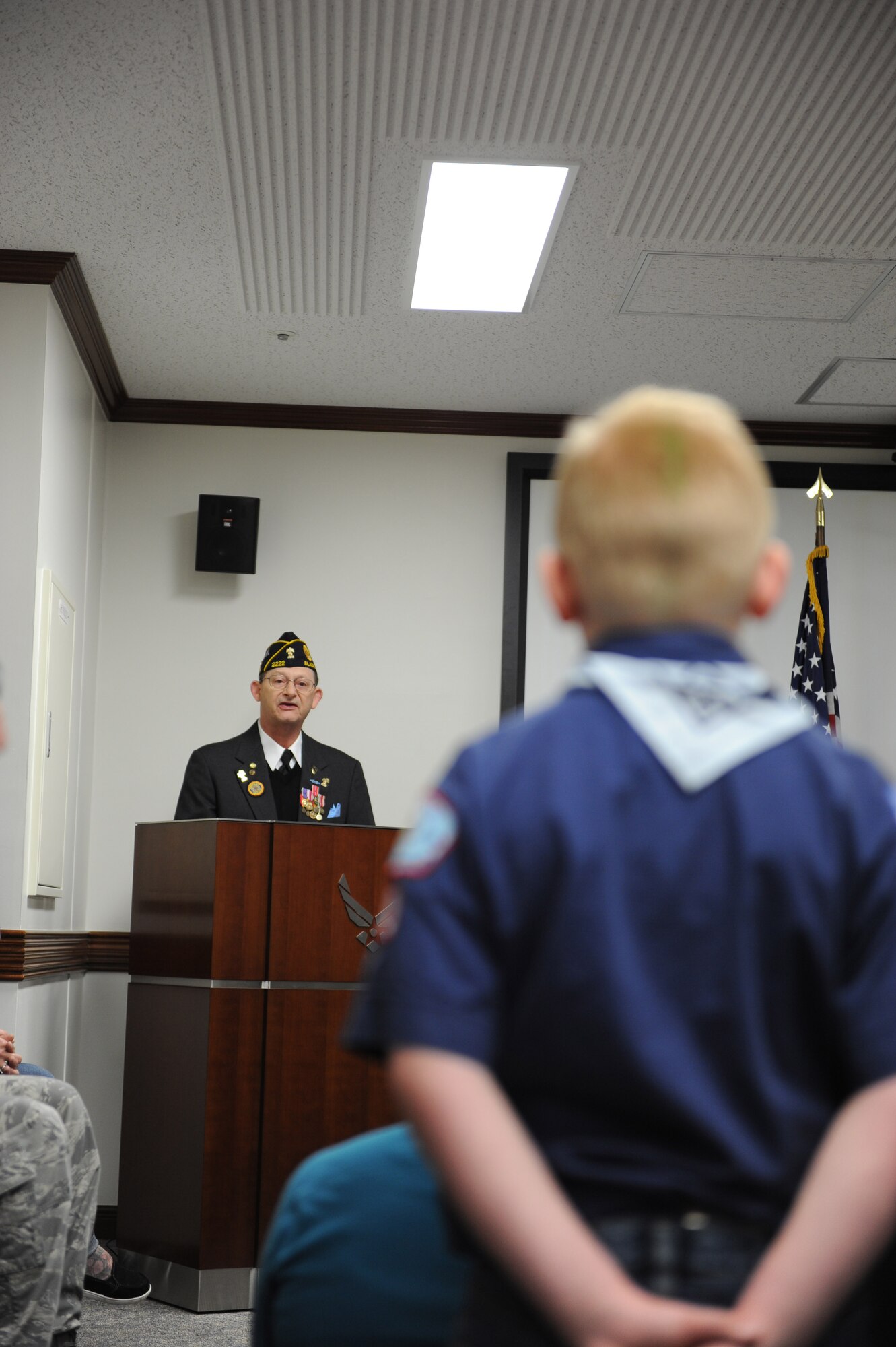 YOKOTA AIR BASE, Japan -- A Scout looks on as Mr. John Pierce, commander of the American Legion post 2222 gives remarks during an indoor Veteran's Day ceremony at the 374th Airlift Wing Headquarters' conference room here, November 11, 2011. Bad weather forced base leadership to cancel the outdoor ceremony, but Yokota scouts chose to show up despite the weather. (U.S. Air Force photo/Capt. Raymond Geoffroy)