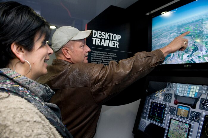 Hoss Clack, British Aerospace Electronic Systems consultant, shows Fiona Ingalls how to use a Hawk Advance Jet Training simulator during the 2011 Aviation Nation Open House naturalization ceremony Nov. 11, at Nellis Air Force Base, Nev. Aviation Nation celebrates 70 years of airpower in Las Vegas and the Air Force's accomplishments in air, space and cyberspace. (U.S. Air Force photo by Airman 1st Class Matthew Lancaster/Released)
