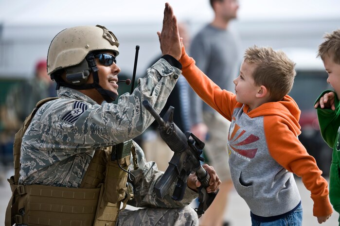Owen George, son of Adam George, gives Tech. Sgt. Ramon Padilla, 820th RED HORSE airborne flight airborne electrical systems craftsman, a high five during the 2011 Aviation Nation Open House Nov. 13, at Nellis Air Force Base, Nev. Aviation Nation celebrates 70 years of airpower in Las Vegas and the Air Force's accomplishments in air, space and cyberspace. (U.S. Air Force photo by Senior Airman Brett Clashman/Released)