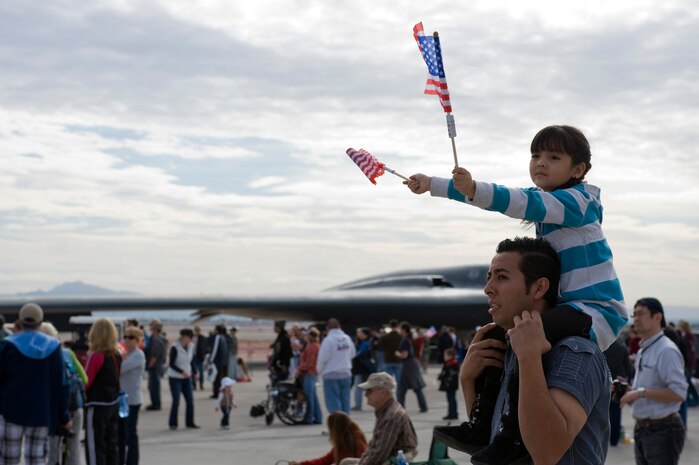 Naomi Rosales, 5 years old, waves an American flags while sitting on her father's, Hebeir Rosales, shoulders during the 2011 Aviation Nation Open House naturalization ceremony Nov. 11, at Nellis Air Force Base, Nev. Aviation Nation celebrates 70 years of airpower in Las Vegas and the Air Force's accomplishments in air, space and cyberspace. (U.S. Air Force photo by Airman 1st Class Matthew Lancaster/Released)