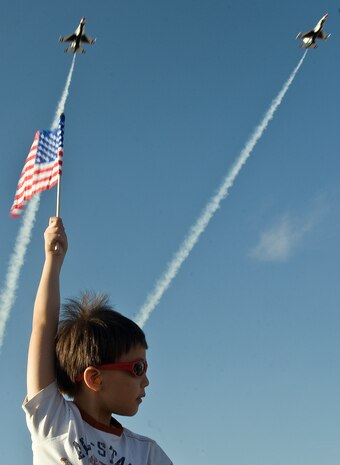 A boy holds up an American Flag as the United States Air Force Air Demonstration Squadron Thunderbirds, fly overhead during the 2011 Aviation Nation Open House Nov. 12, at Nellis Air Force Base, Nev. Aviation Nation celebrates 70 years of airpower in Las Vegas and the Air Force's accomplishments in air, space and cyberspace. (U.S. Air Force photo by Staff Sgt. Christopher Hubenthal/Released)
