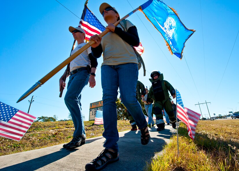 Staff Sgt. Tannia Dillon, of the Army Explosive Ordnance Disposal Training Detachment, leads a group of Army EOD techs by Lewis Middle School during the Veteran's Day Walk Nov. 11 at Eglin Air Force Base, Fla.  Army EOD techs took turns walking from Eglin to the EOD Memorial in the 79-pound bomb suit in two-person teams.  The detachment commander and sergeant major walked the first mile.  (U.S. Air Force photo/Samuel King Jr.) 