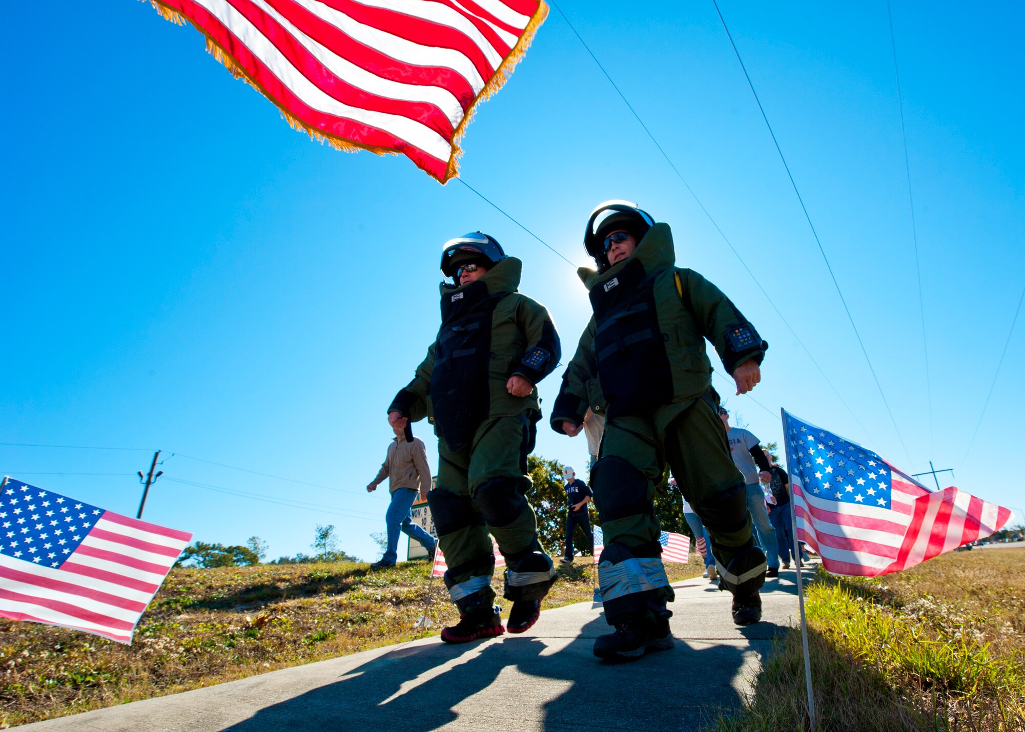 Sgt. Maj. Patrick Standley and Lt. Col. Mark Krussow, of the Army Explosive Ordnance Disposal Training Detachment, pass by Lewis Middle School walking in the EOD bomb-suit during the Veteran's Day Walk Nov. 11 at Eglin Air Force Base, Fla.  Army EOD techs took turns walking from Eglin to the EOD Memorial in the 79-pound bomb suit in two-person teams.  The detachment commander and sergeant major walked the first mile. (U.S. Air Force photo/Samuel King Jr.)