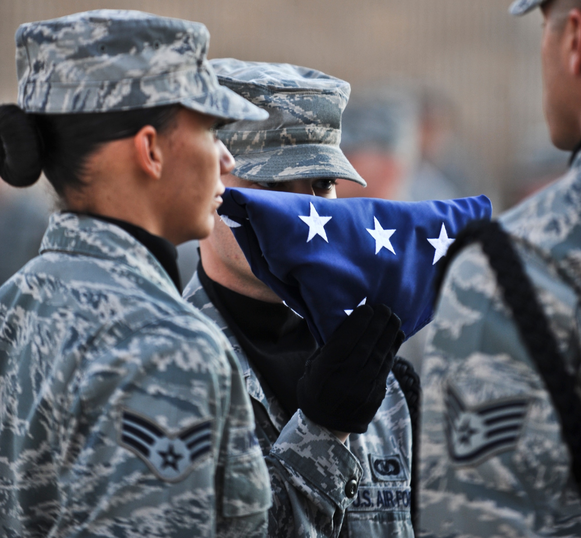 Senior Airman Jared Barlett, 379th Expeditionary Operations Support Squadron aircrew flight equipment journeyman, raises a folded American flag during a Veterans Day ceremony Nov. 11, 2011, at an undisclosed location in Southwest Asia. Barlett, a native of Wichita, Kan., is deployed from McConnell Air Force Base, Kan., (U.S. Air Force photo/Senior Airman Paul Labbe)