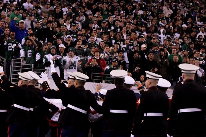 EAST RUTHERFORD, N.J. -- Marines wave back to a cheering crowd after a pregame ceremony before the  the New York Jets vs New England Patriots game, Nov. 13. The West Point Band performed at half time and 100 service members presented the large flag during the National Anthem. (Official Marine Corps photo by Sgt. Randall A. Clinton / RELEASED)