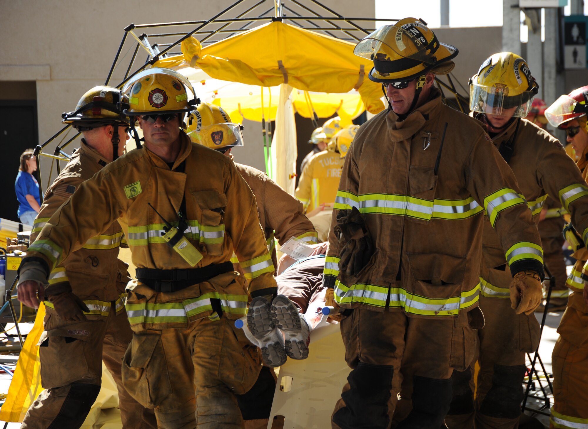 Firefighters carry victims with simulated critical injuries away from the decontamination tent during the Tucson Metropolitan Medical Response Systems exercise held in Tucson, Ariz., Nov. 10, 2011. The scenario used during the exercise involved chemical pollution and required players to determine who was contaminated and then execute proper decontamination procedures. (U.S. Air Force photo by Airman 1st Class Saphfire Cook/Released)