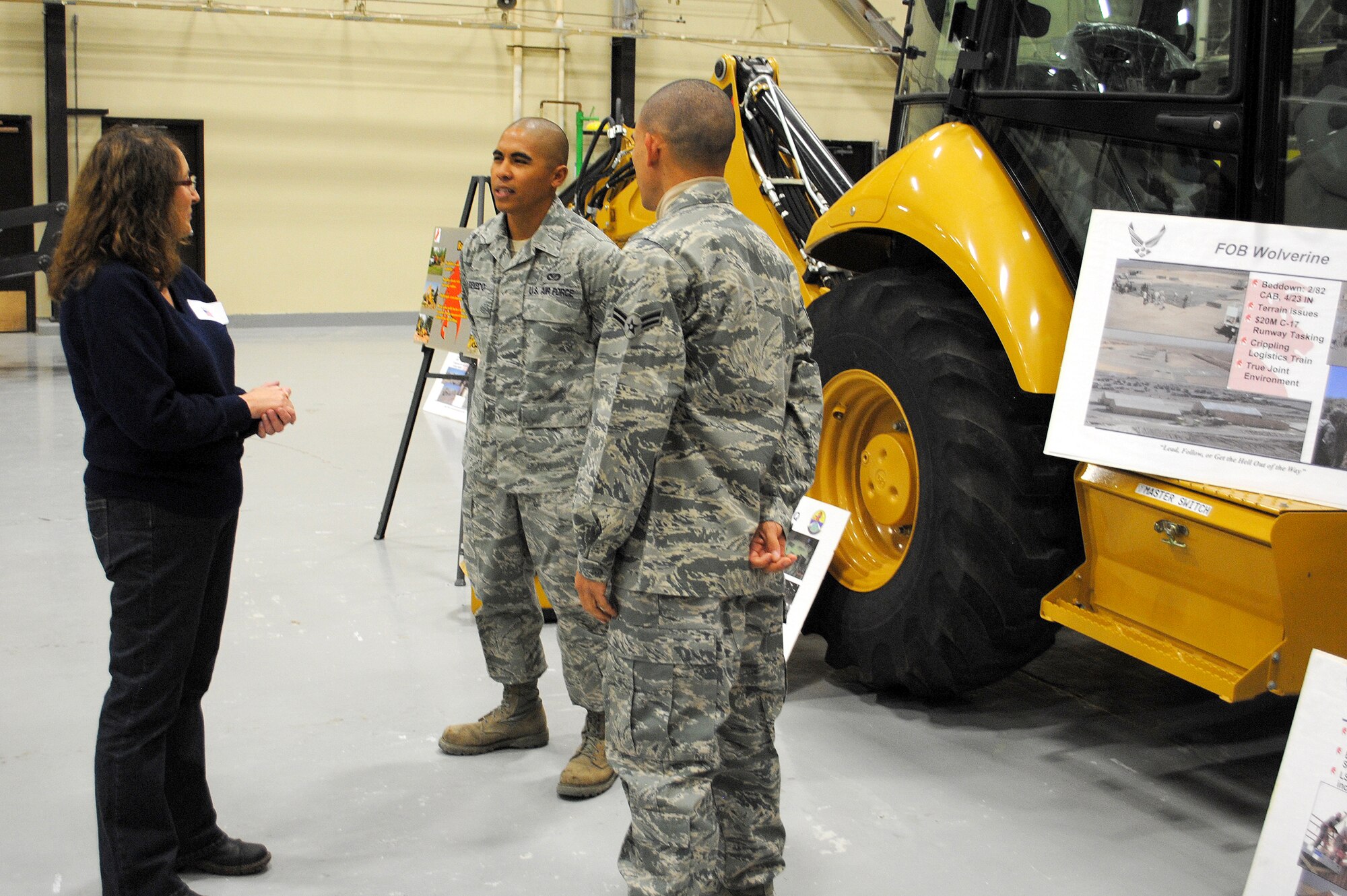 Debbie Lewis, a CIVAIRES member, speaks to Staff Sgt. Antonio Ecevedo, 819th RED HORSE Squadron heavy equipment operator (left), and Airman 1st Class Cecilio Fantauzzi, pavements and equipment apprentice, about the backhoe behind them, and their experience as part of the RED HORSE Squadron. The backhoe was one of several types of equipment on display during the CIVAIRES tour. (U.S. Air Force photo/Airman Cortney Paxton)