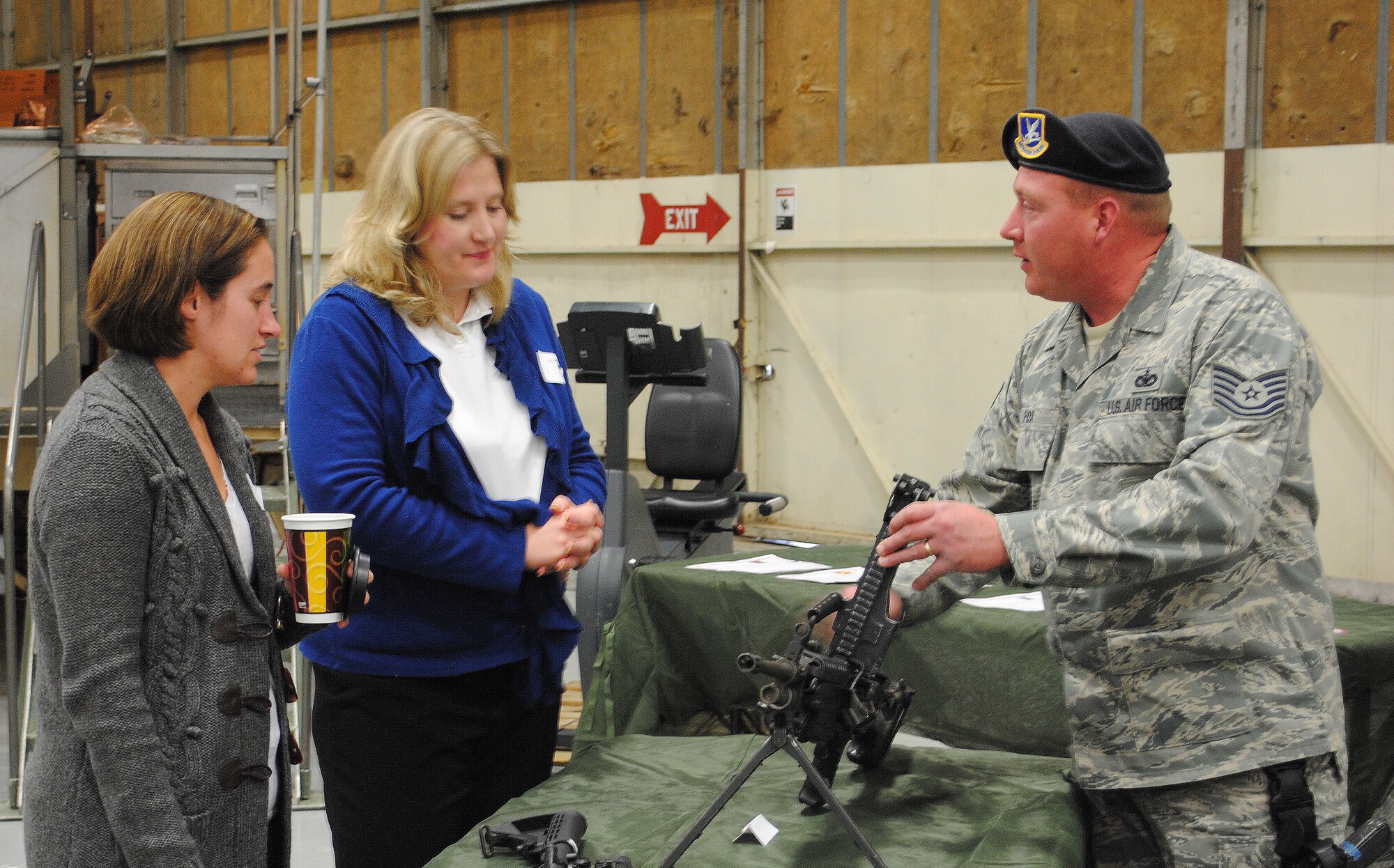 Tech. Sgt. Mathew Fox, 819th RED HORSE Squadron security manager, shows Beth Zimmerhanzel and Rory Cullen, both members of the CIVAIRES program, the different parts of a weapon. The members of the CIVAIRES program all had a chance to browse several different displays around the RED HORSE hangar during a luncheon Nov. 1. (U.S. Air Force photo/Airman Cortney Paxton)