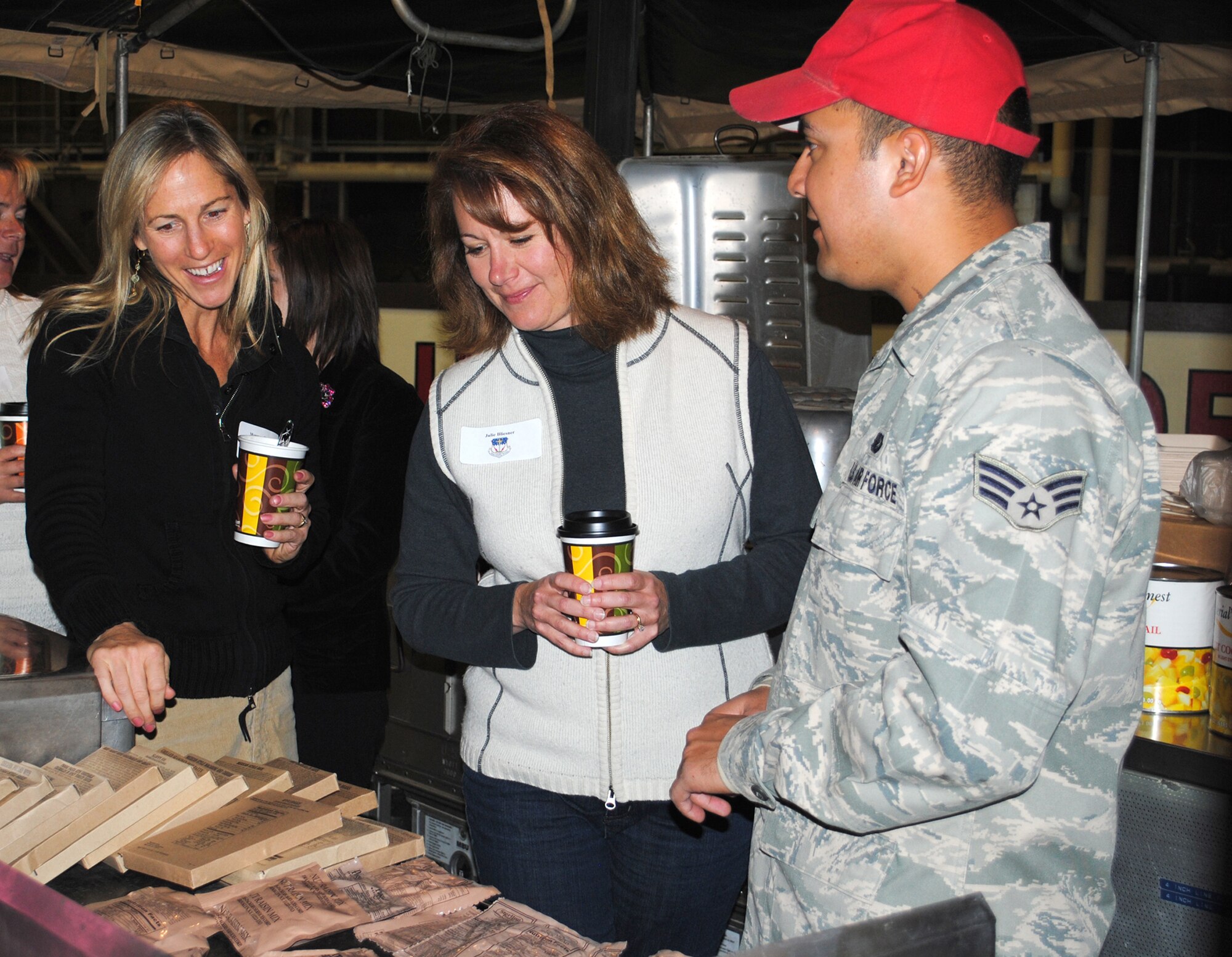 Senior Airman Miguel Rimirez, 819th RED HORSE Squadron services journeyman, explains to Maureen Guenther and Julie Bliesner what Meals Ready to Eat are and what his favorite is. CIVAIRES members were able to taste test the MREs during their orientation tour of the 819th RHS on Nov. 1.