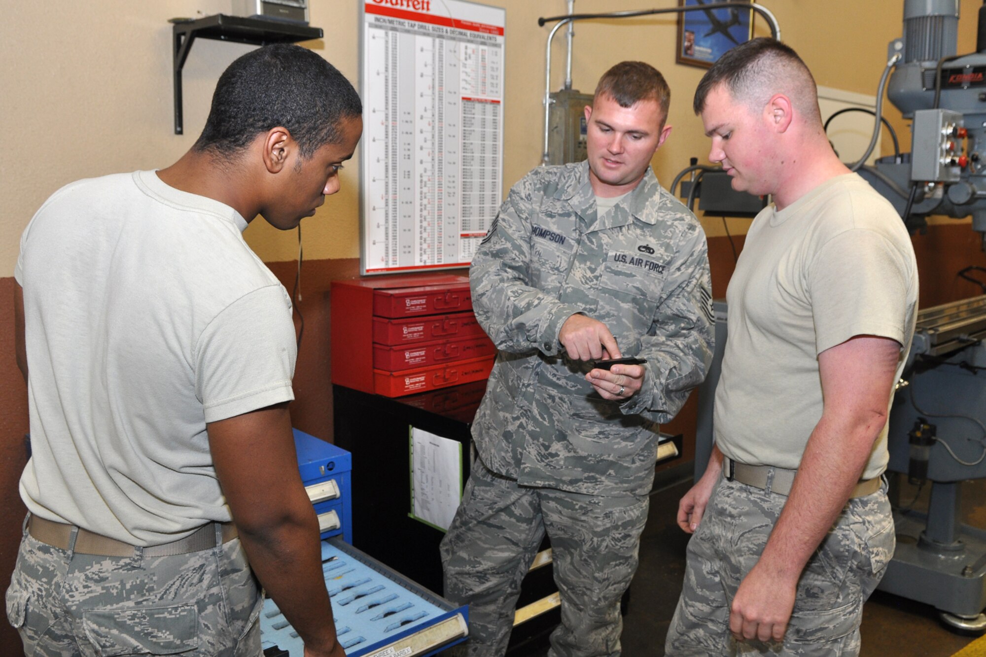 Airman 1st Class Terence Lewis and Senior Airman Carl Lindholm, listen as Tech. Sgt. Ryan Thompson, who is the fabrication flight chief for the 707th Maintenance Squadron, explains how to identify, properly mark and account for machine tooling at Barksdale Air Force Base, La., Nov. 8, 2011. Lewis, who is a metals technologist apprentice, and Lindholm, who is a metals technologist journeyman, are both assigned to the 2nd Maintenance Squadron. The Airmen are preparing for an inspection. (U.S. Air Force photo by Master Sgt. Jeff Walston/Released) 