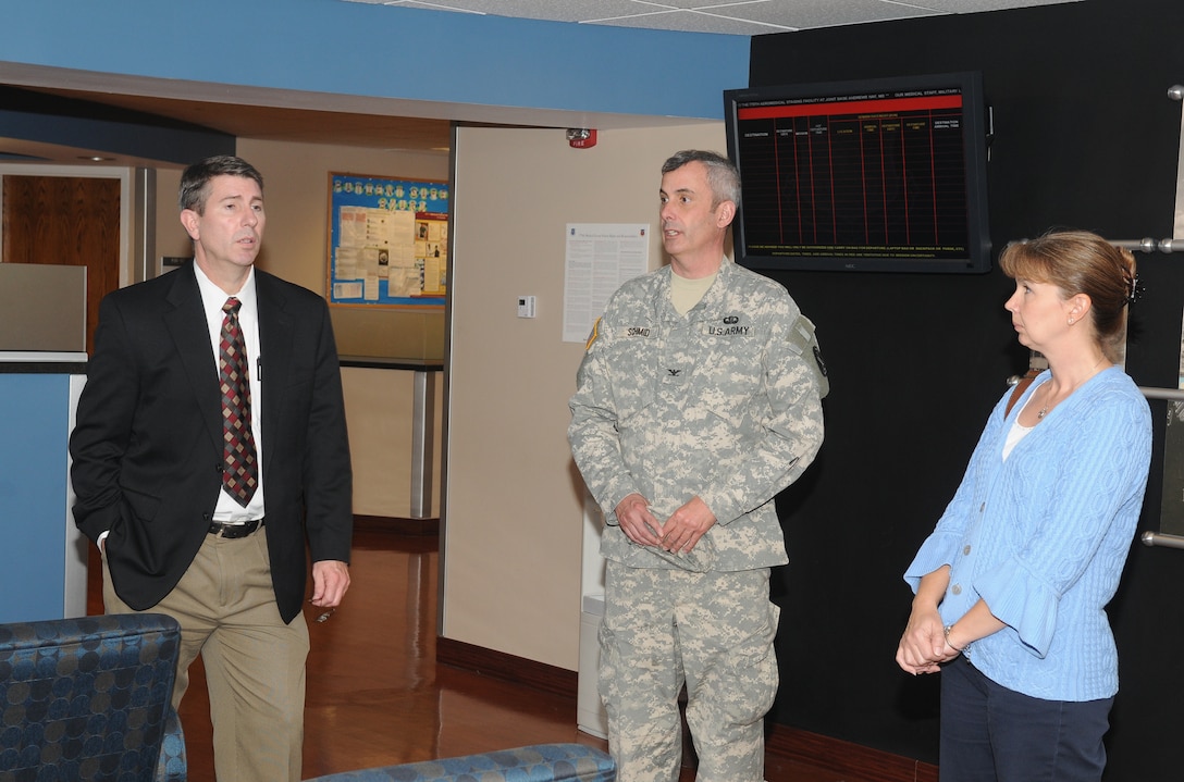 Eldon Mullins, Headquarters Army Emergency Relief deputy director for administration, and Melissa LaValle, assistant treasurer, listen as Col. Claude Schmidt, 779th Medical Group Aerospace Staging Facility senior Army liaison officer, shares information on the importance of AER to Wounded Warriors transiting the ASF during a tour Nov. 9, 2011, Joint Base Andrews, Md. (U.S. Air Force Photo by Aletha Frost)  