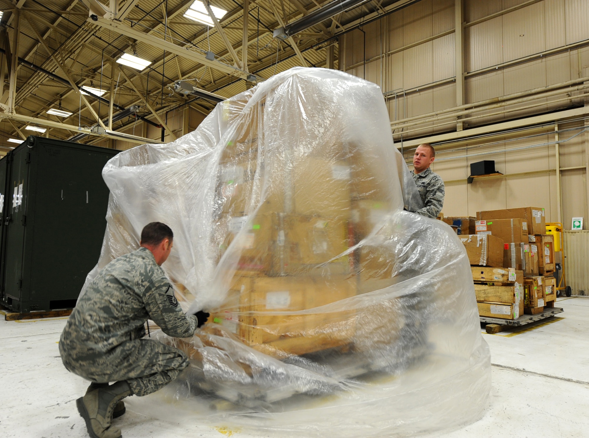 Master Sgt. Jeremy Heideman and Senior Airman Cody Wyatt, 28th Logistics Readiness Squadron aircraft parts store technicians, wrap a pallet of aircraft parts at Dock 63 on Ellsworth Air Force Base, S.D., Nov. 3, 2011. The crates are wrapped and secured to protect the parts during transit to deployed locations. (U.S. Air Force photo by Airman 1st Class Zachary Hada/Released)