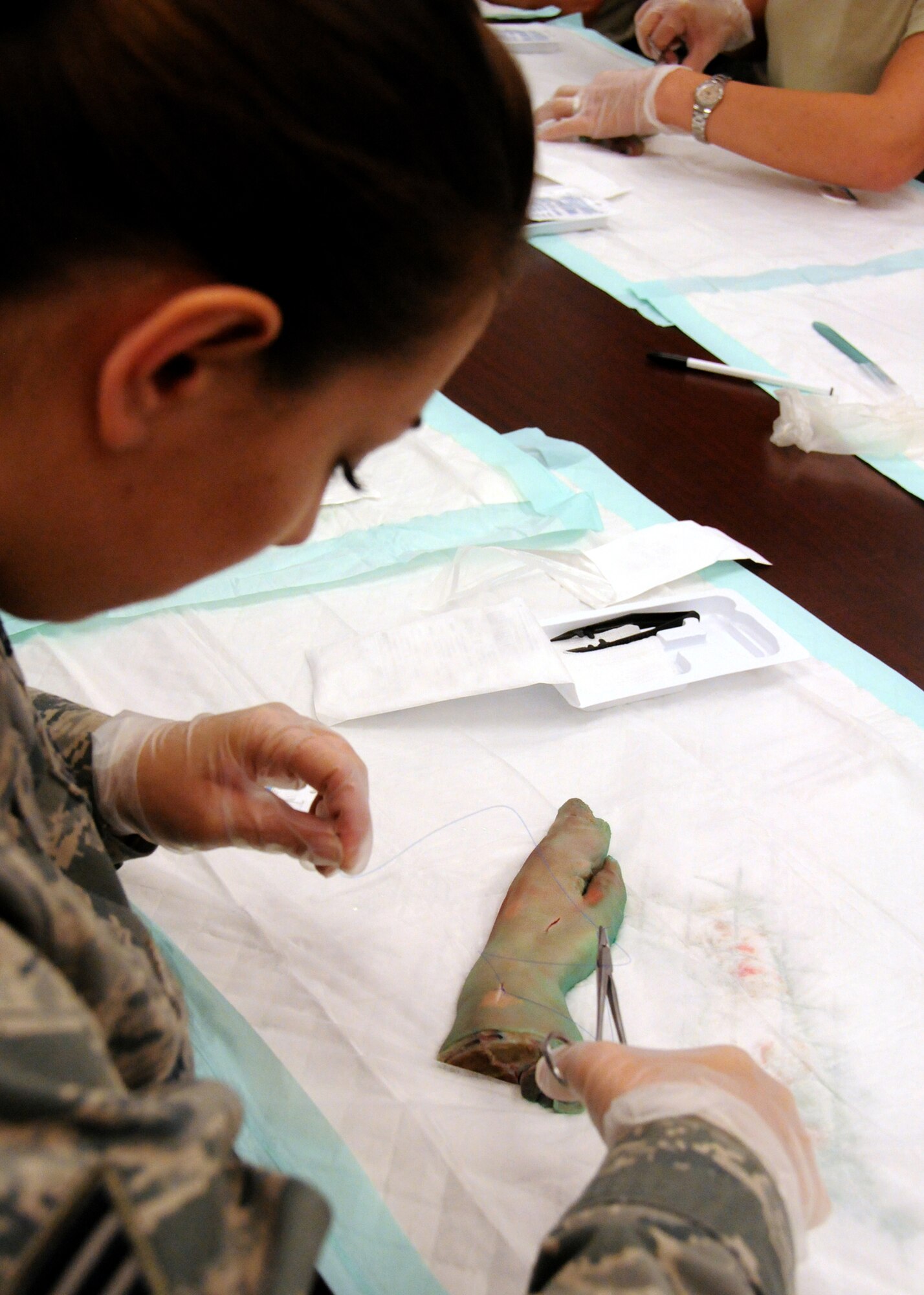 Air Force Reserve Senior Airman Candice Winn of the 919th Medical Squadron ties a stitch for a simple suture on a pig’s foot laceration at Duke Field, Fla., Nov. 6.  The 919th MDS conducted training on simple- interrupted sutures and mattress sutures using pigs’ feet during the November unit training assembly. (U.S. Air Force photo/Tech. Sgt. Cheryl L. Foster)