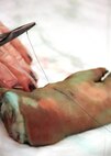An Airman pulls a thread for a simple suture on a pig’s foot laceration at Duke Field, Fla., Nov 6.  The 919th Medical Squadron conducted training on simple- interrupted sutures and mattress sutures using pigs’ feet during the November unit training assembly. (U.S. Air Force photo/Tech. Sgt. Cheryl L. Foster)
